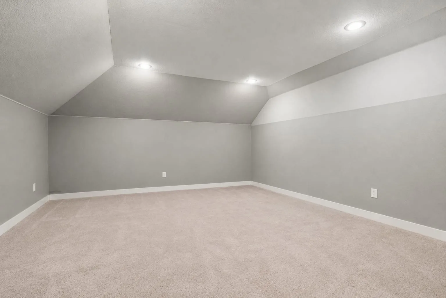 Recessed lighting illuminates an expansive room featuring carpeting and neutral wall tones