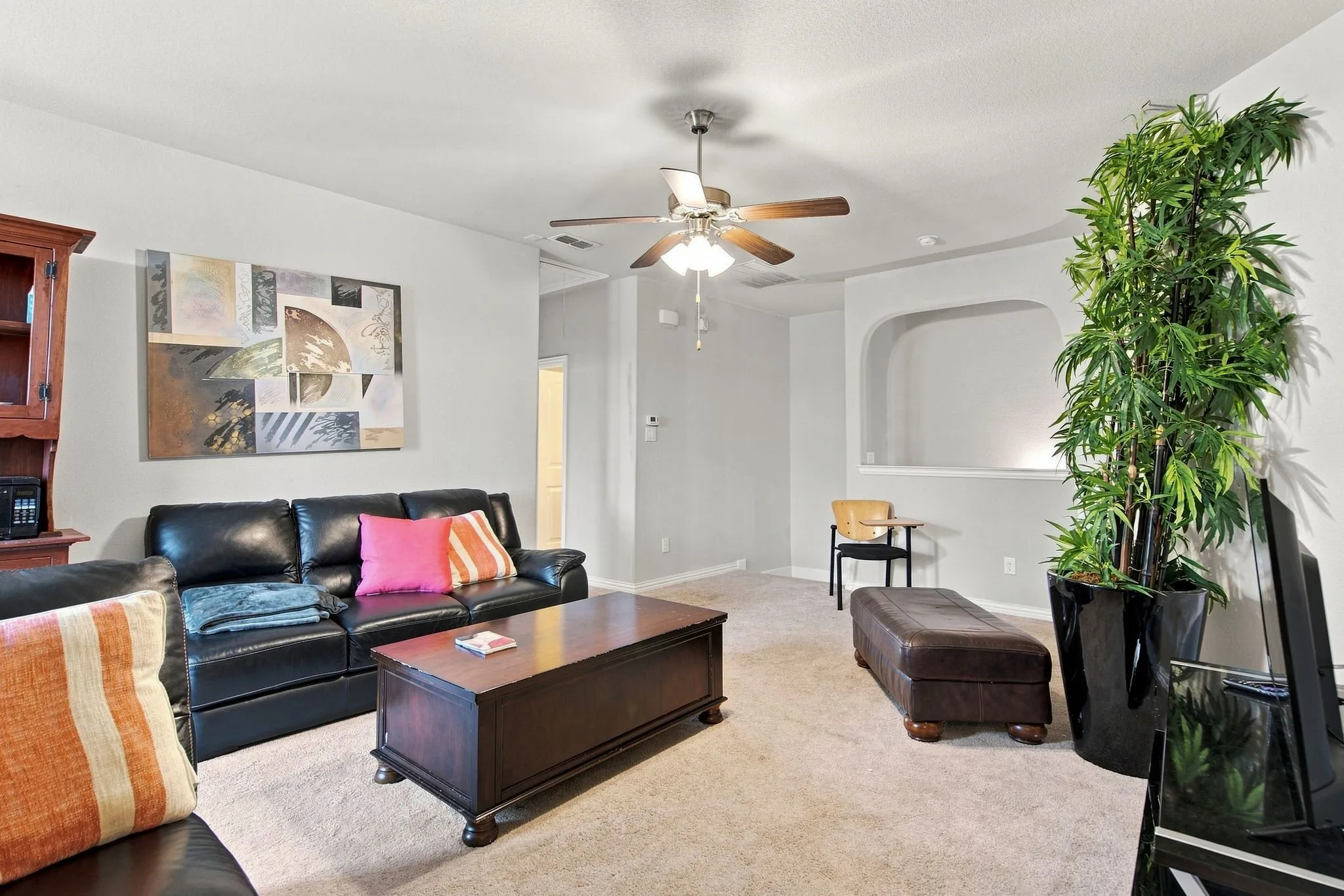 Recessed wall niche, ceiling fan with light fixture, light-colored carpeting, and painted walls