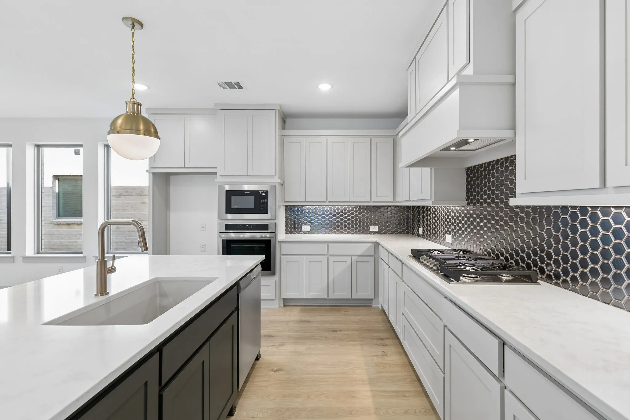 Beautiful two tone cabinetry, gorgeous countertops and statement backsplash effortlessly pair with contemporary stainless steel to create a kitchen for the ages!