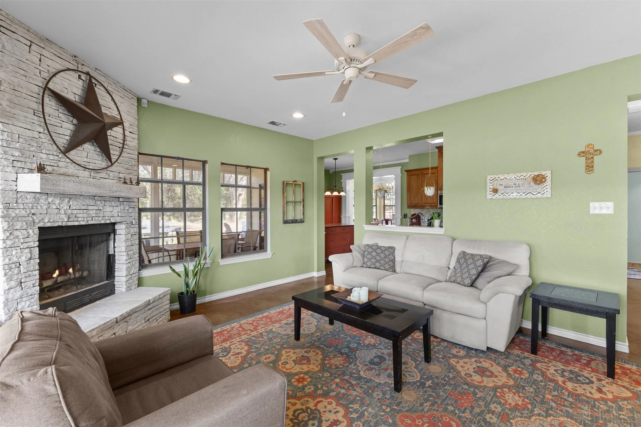 Living area featuring a floor-to-ceiling stacked stone fireplace, a wood mantel, and large multi-pane windows
