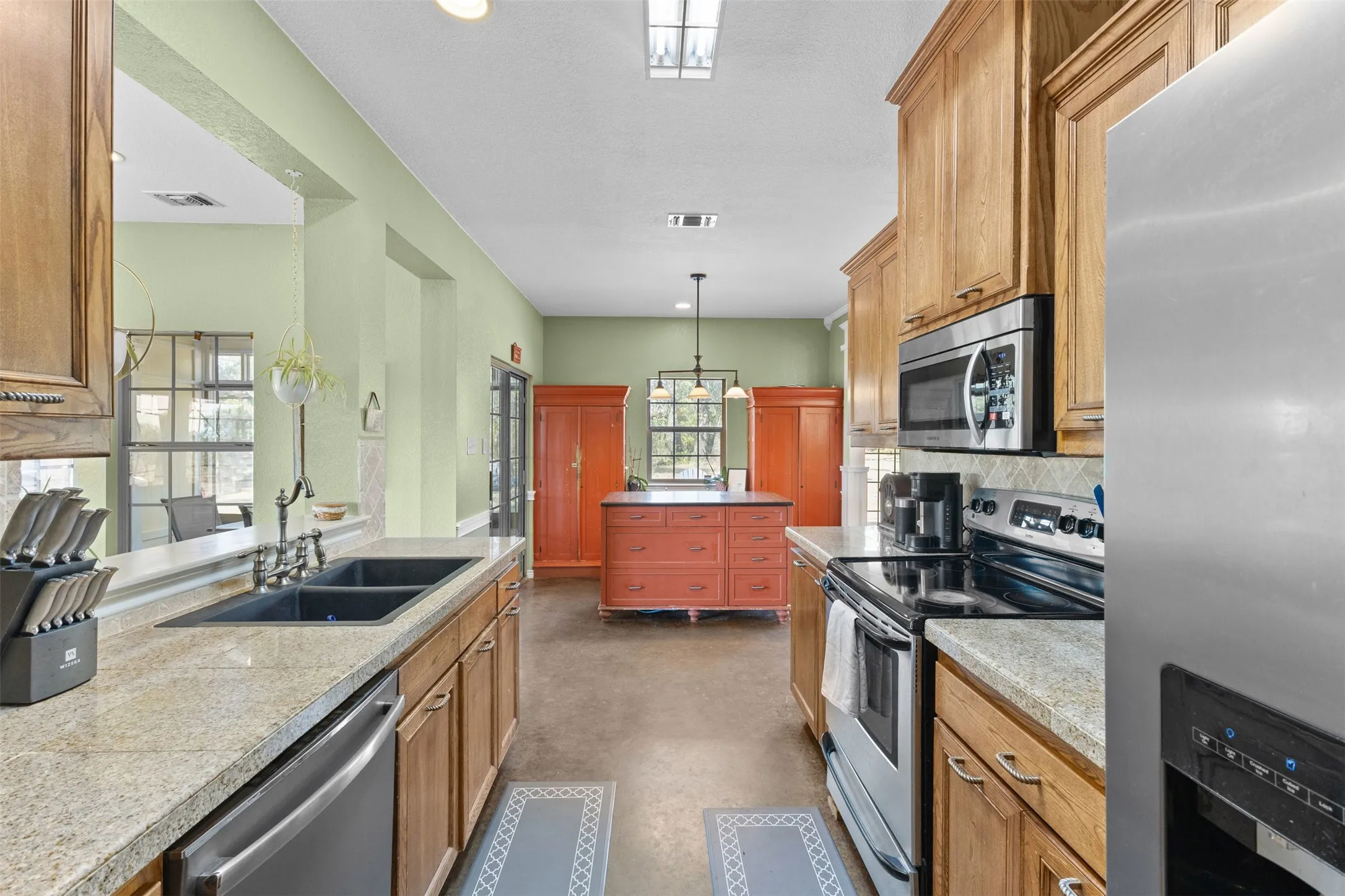 Galley kitchen with light-toned cabinetry, granite-style countertops, stainless steel appliances, and a double basin sink