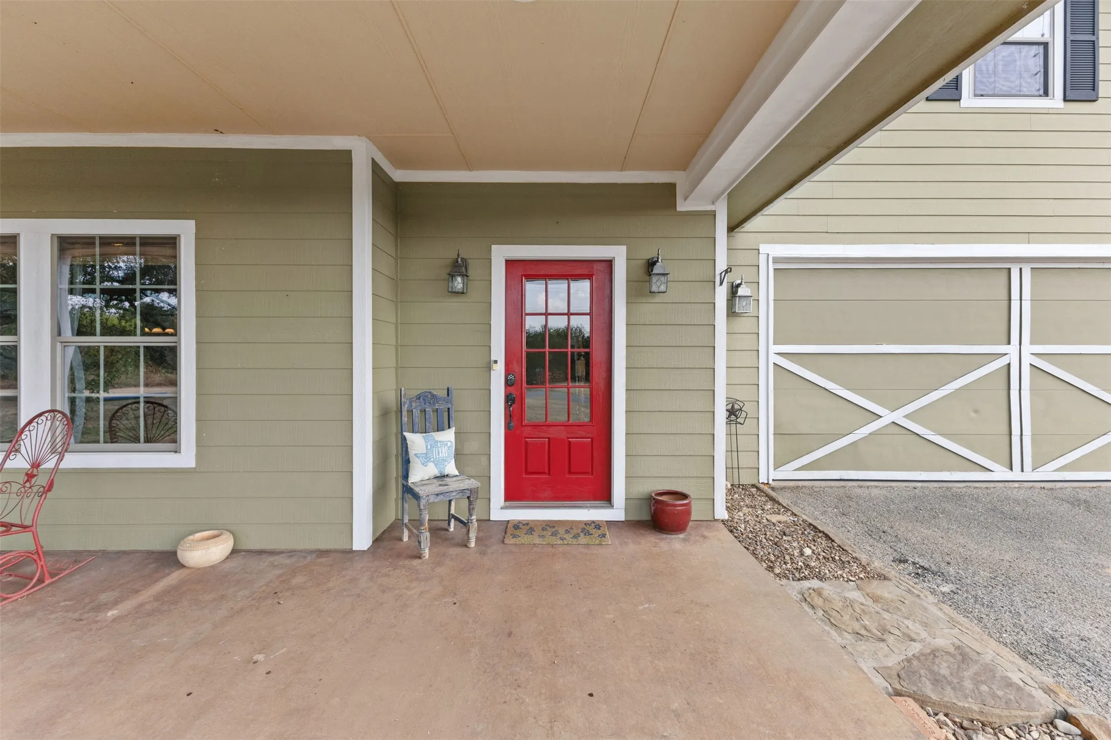 Covered entry with a red door, exterior wall sconces, and light-colored siding