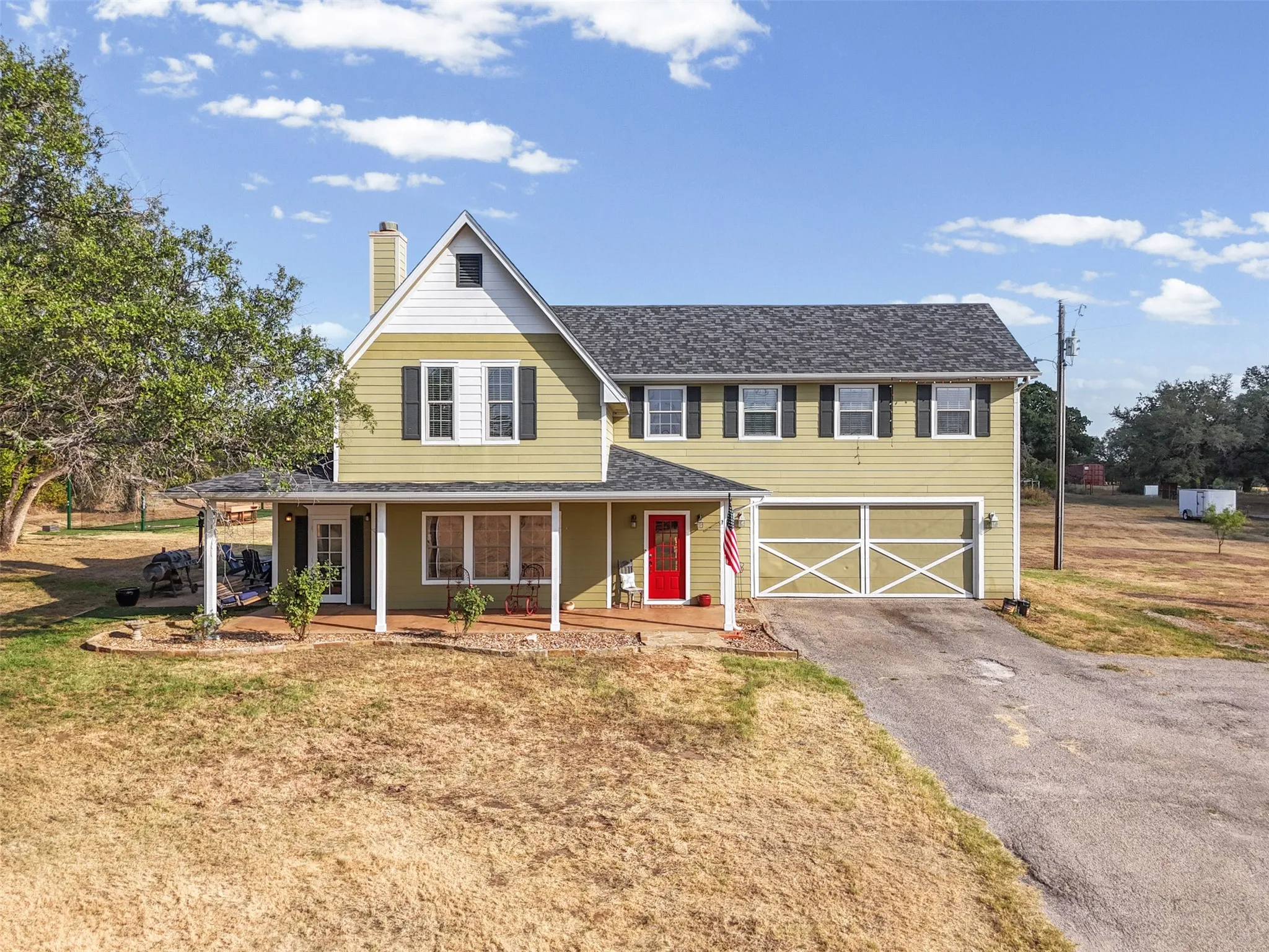 Two-story residence featuring a covered front porch, attached garage with decorative doors, and a prominent gable roofline