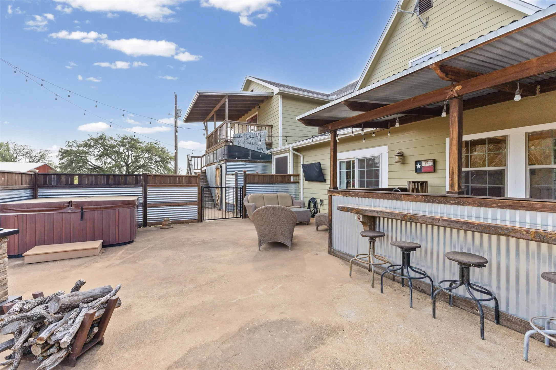 Covered outdoor bar, stone patio, fire pit, and hot tub built for entertaining. A true extension of the living space on this Granbury acreage.