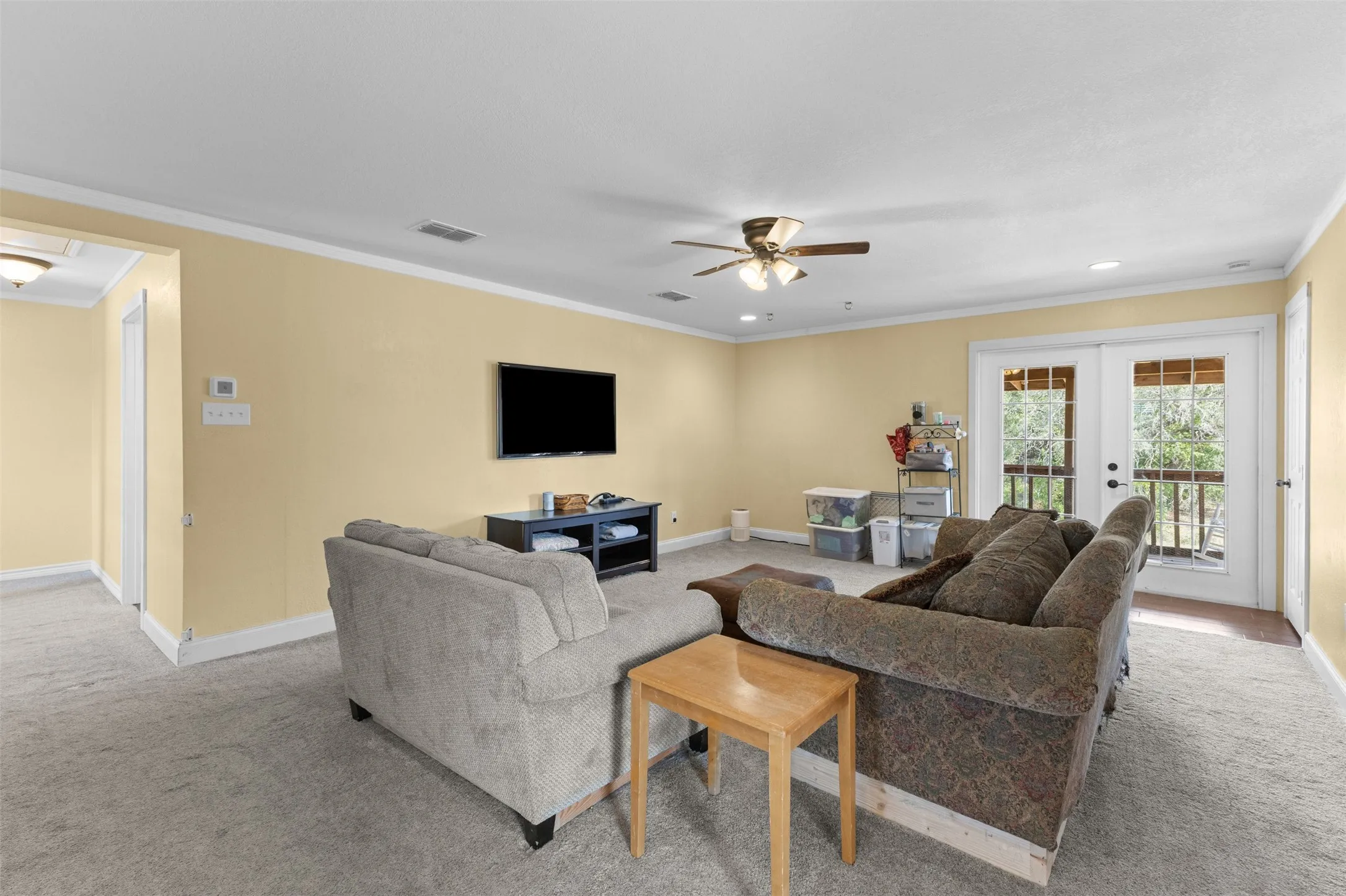 Carpeted living area featuring recessed lighting, a ceiling fan, crown molding, and double glass-paneled doors leading to an outdoor space