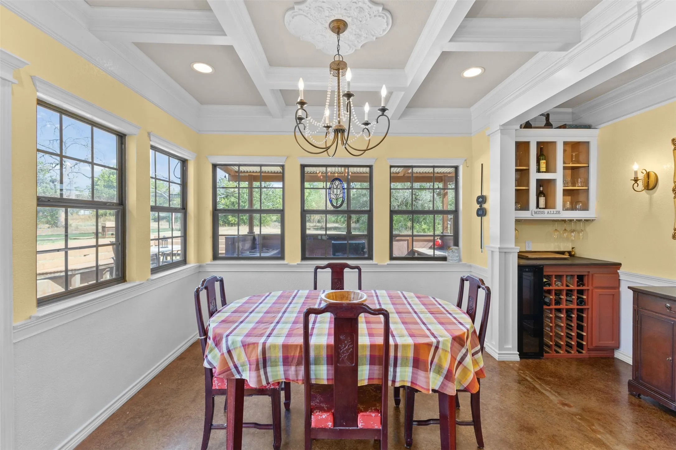 Coffered ceiling with decorative medallion, built-in wet bar with wine storage, multiple large windows, recessed lighting, and wood-finish flooring