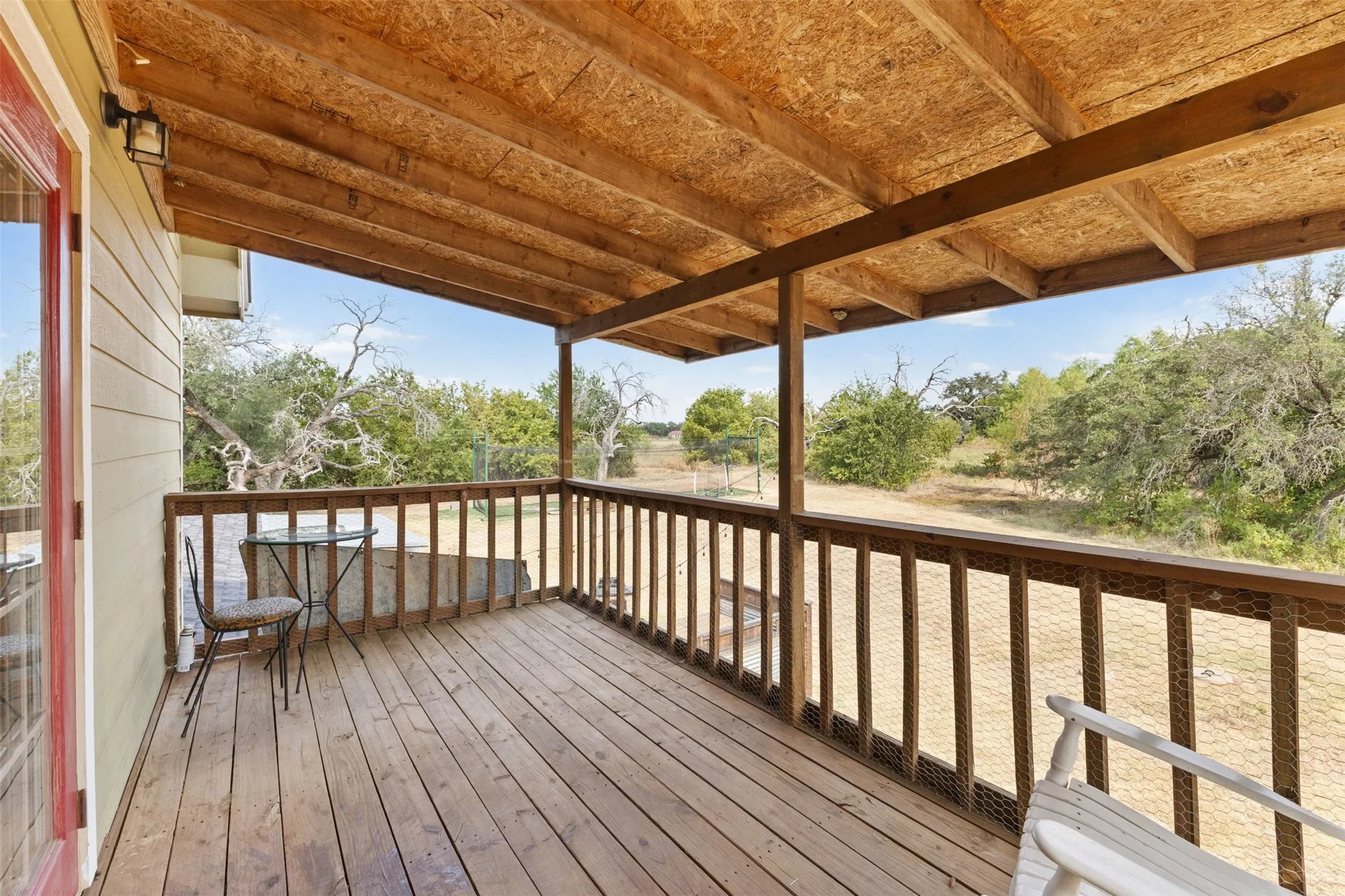 Expansive covered wood deck with wood-plank flooring and a wooden railing