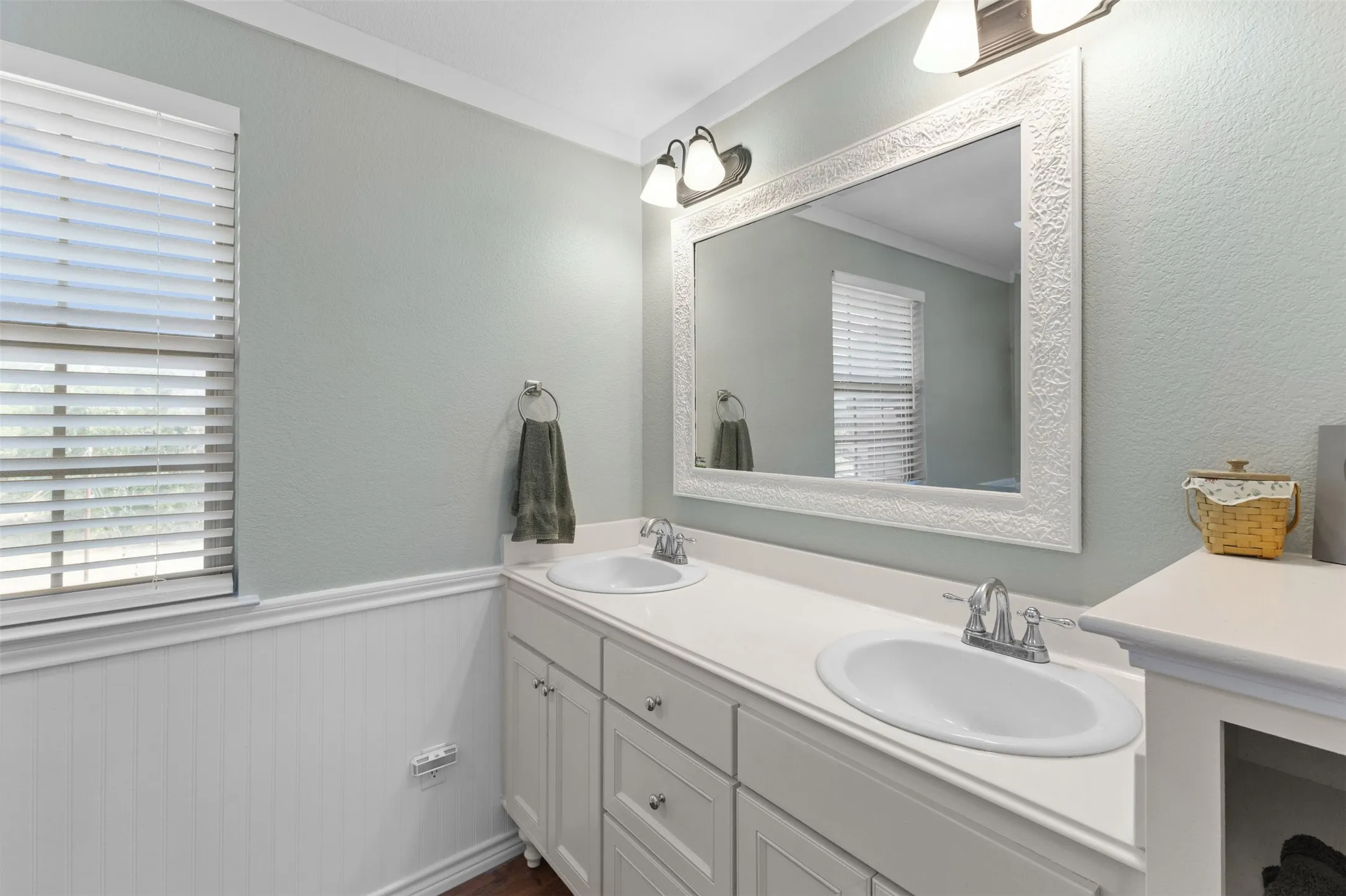 Double vanity with integrated sinks, white cabinetry, and a large decorative framed mirror