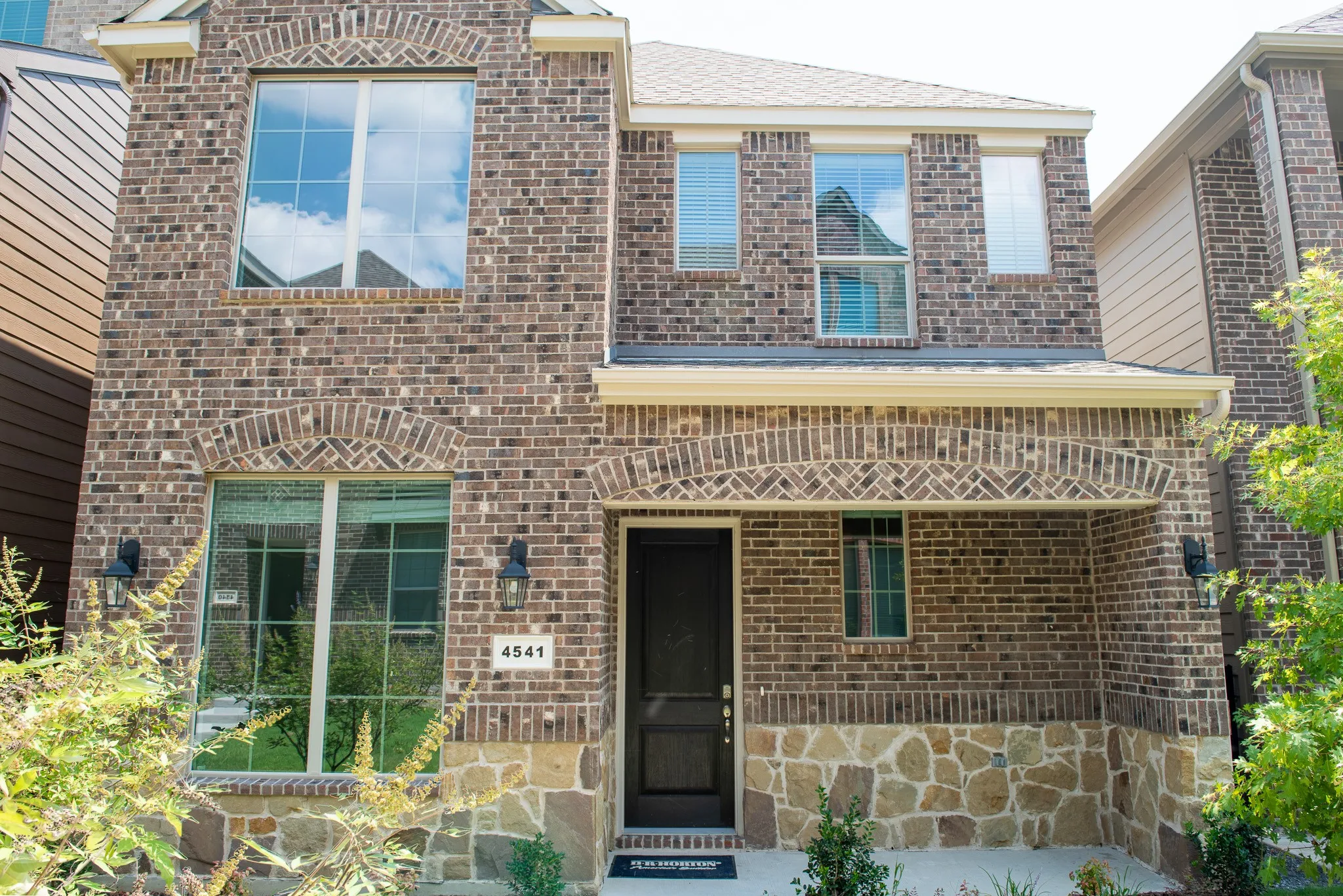 Front elevation showcasing brick and stone exterior with covered entry and modern curb appeal.