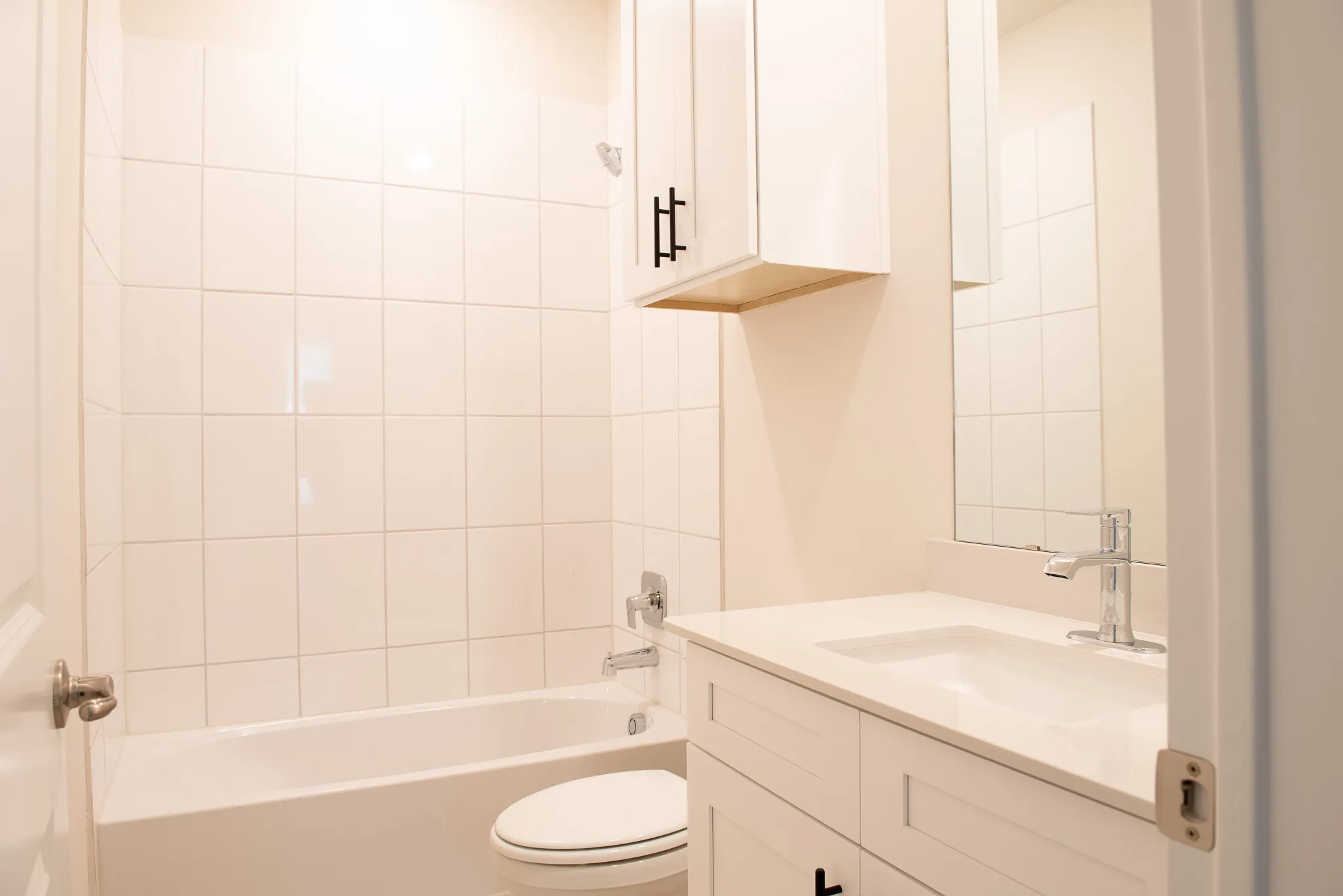 Upstairs bathroom with upgraded tile tub surround, quartz vanity, modern fixtures, and soft-close cabinetry.