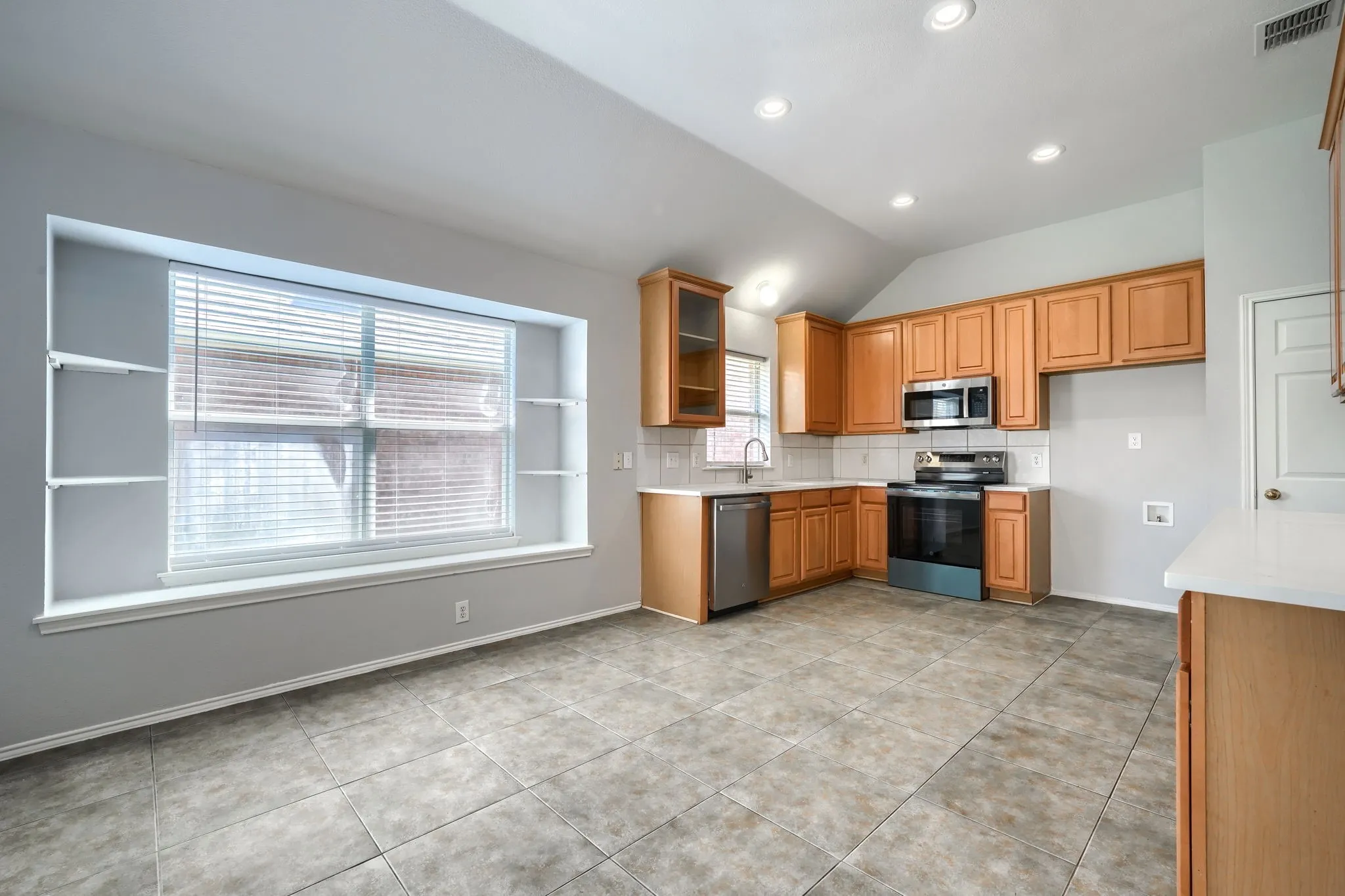 Kitchen featuring wood cabinetry, stainless steel appliances, white countertops, tile flooring, and recessed lighting