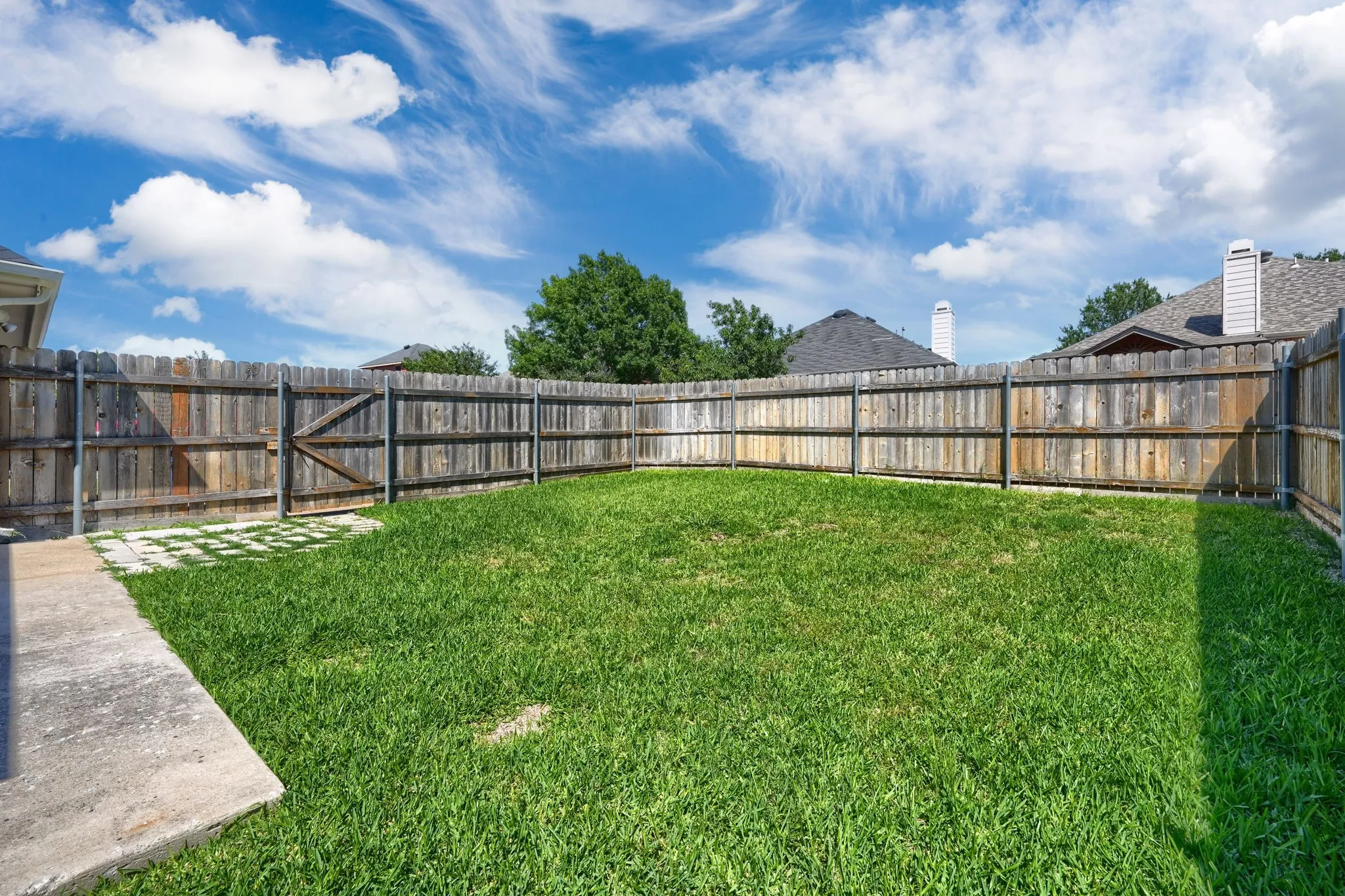 Grassed backyard featuring a wood fence perimeter and a concrete patio