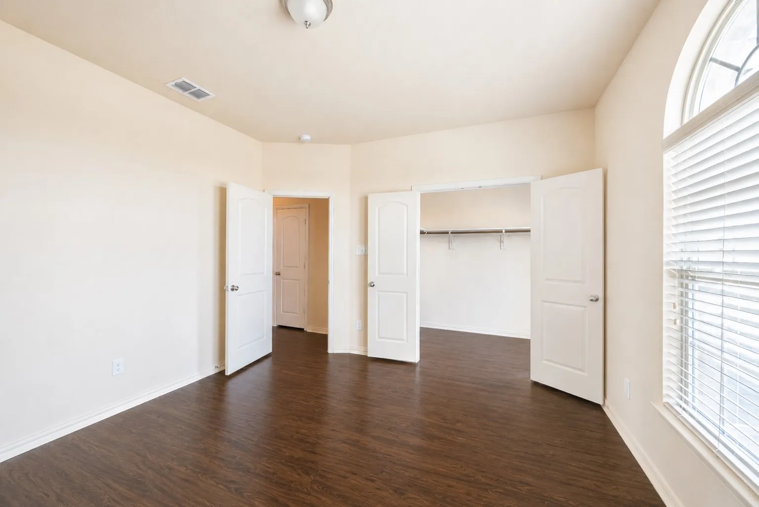 Wood-finish flooring, white paneled doors, and a built-in closet with shelving