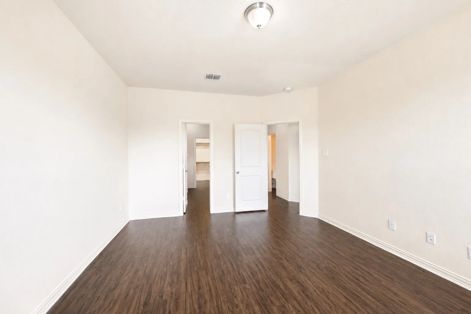 Wood-finish flooring, white walls, and a flush mount ceiling light