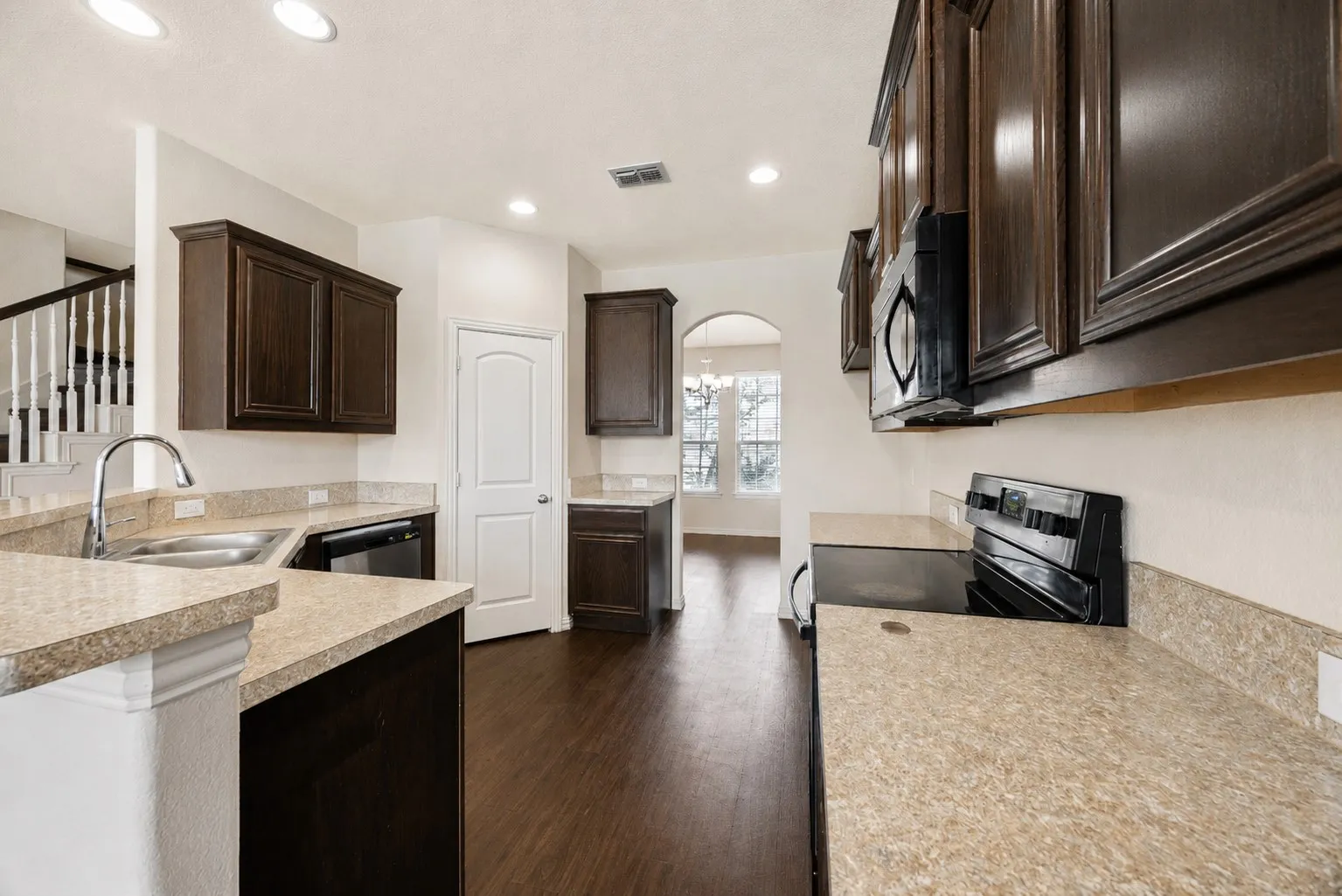 Kitchen featuring dark wood cabinetry, light-toned countertops, wood-finish flooring, and recessed lighting