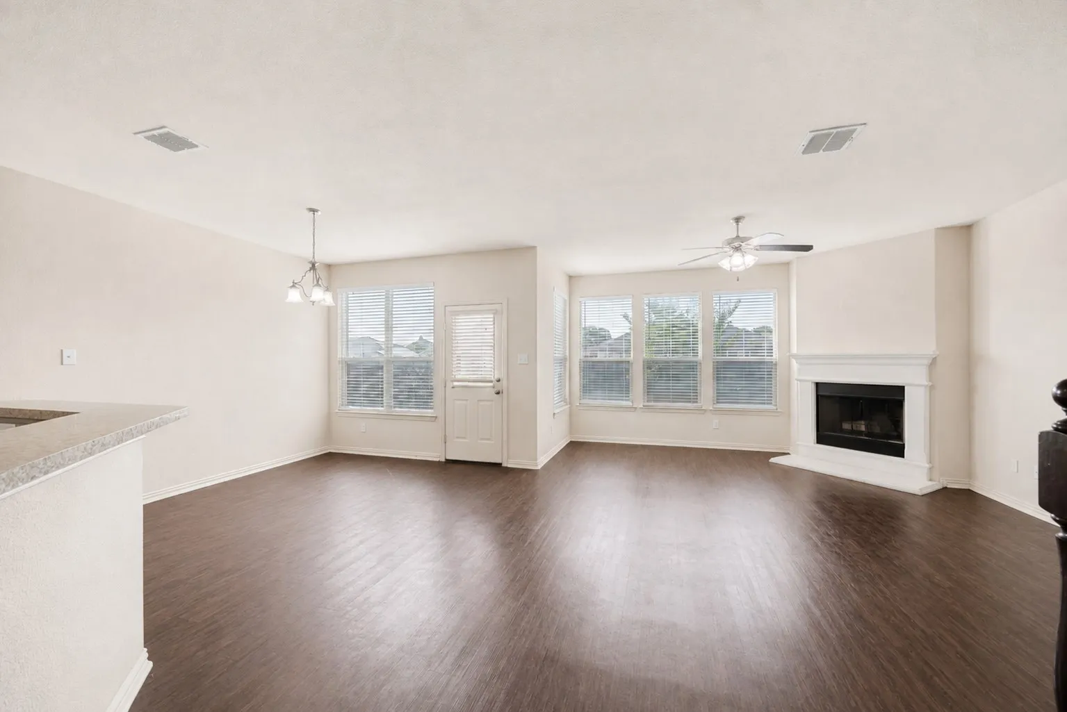 Expansive room with wood-finish flooring, a built-in fireplace, and multiple windows