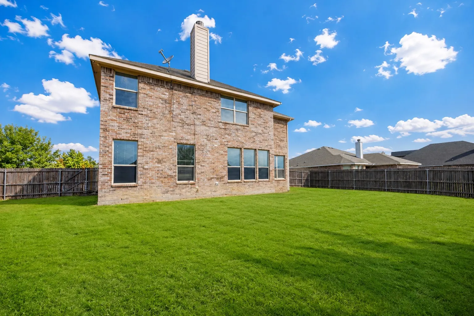 Expansive grassy yard with a full privacy fence