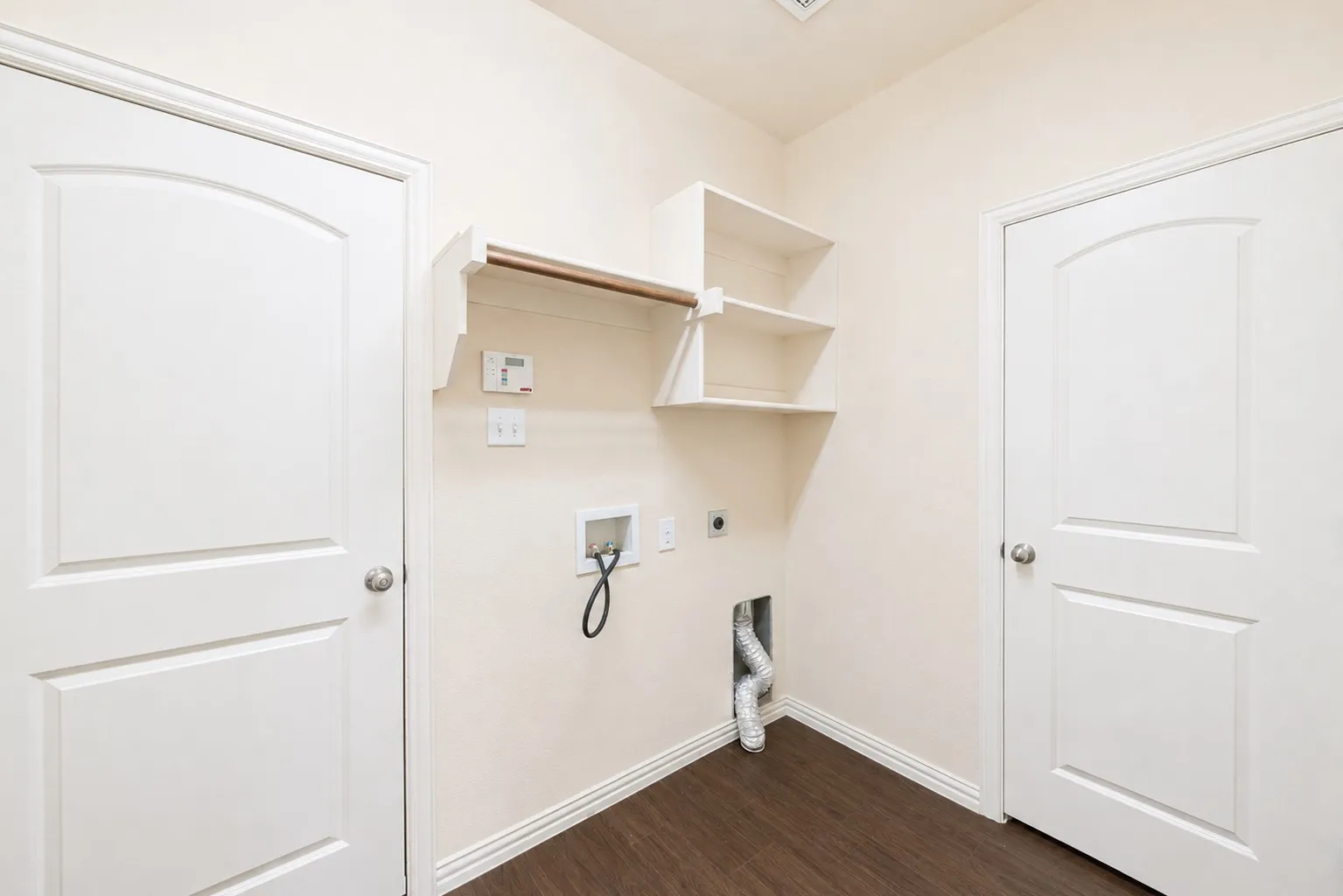 Laundry area with wood-finish flooring, built-in shelving, and a hanging rod