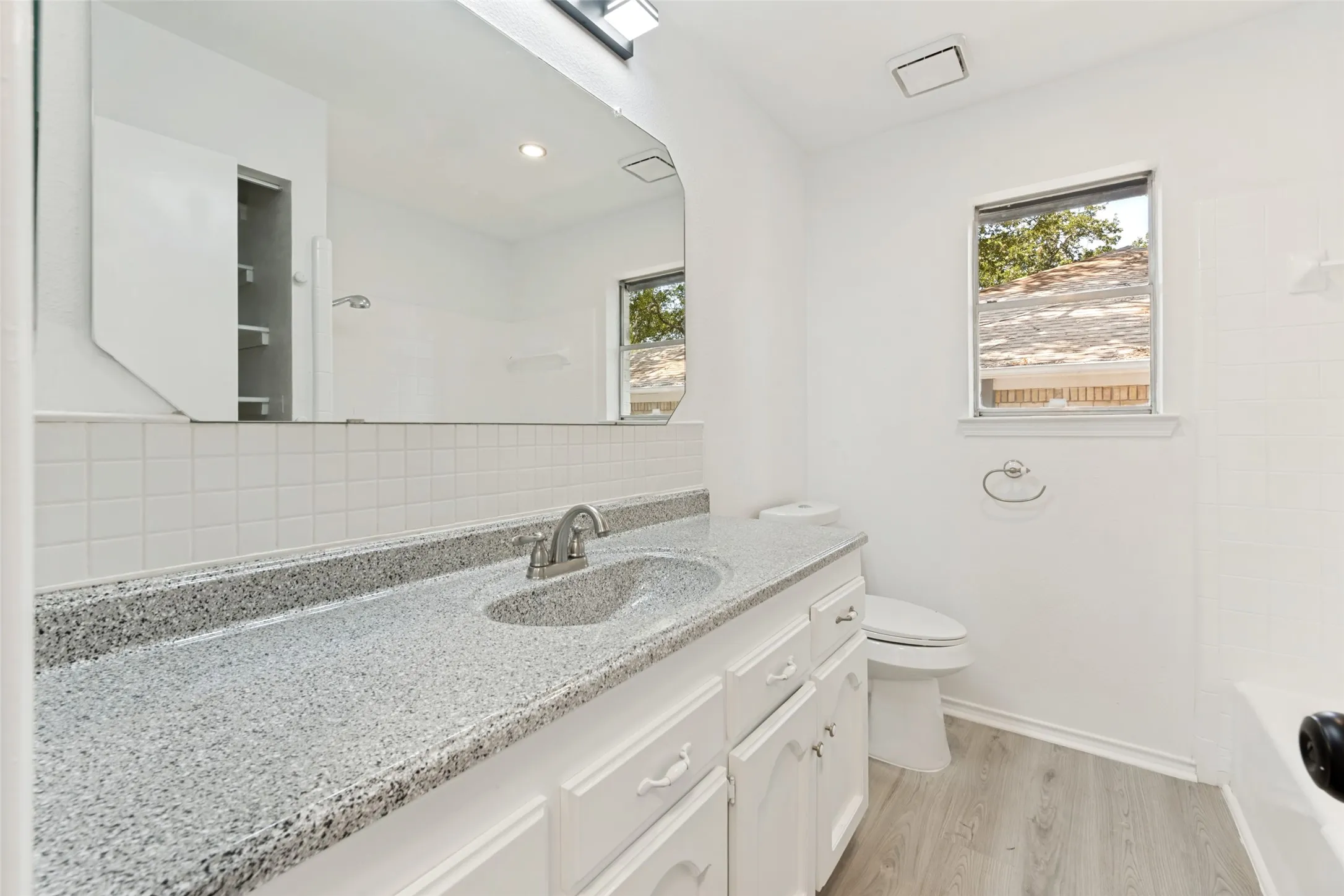 White vanity with cabinet storage, integrated sink, and light-toned countertop