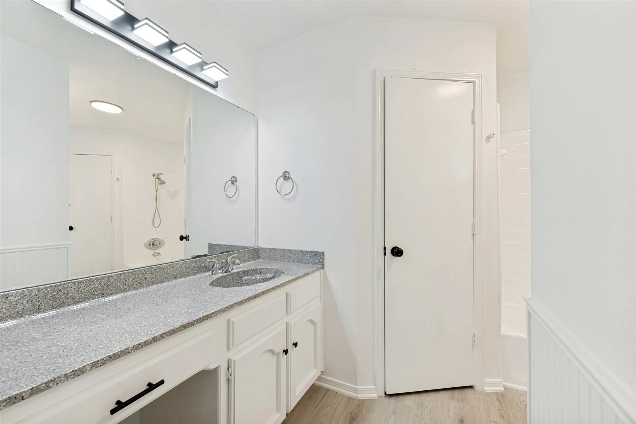 Vanity with a speckled countertop, integrated sink, and white cabinetry