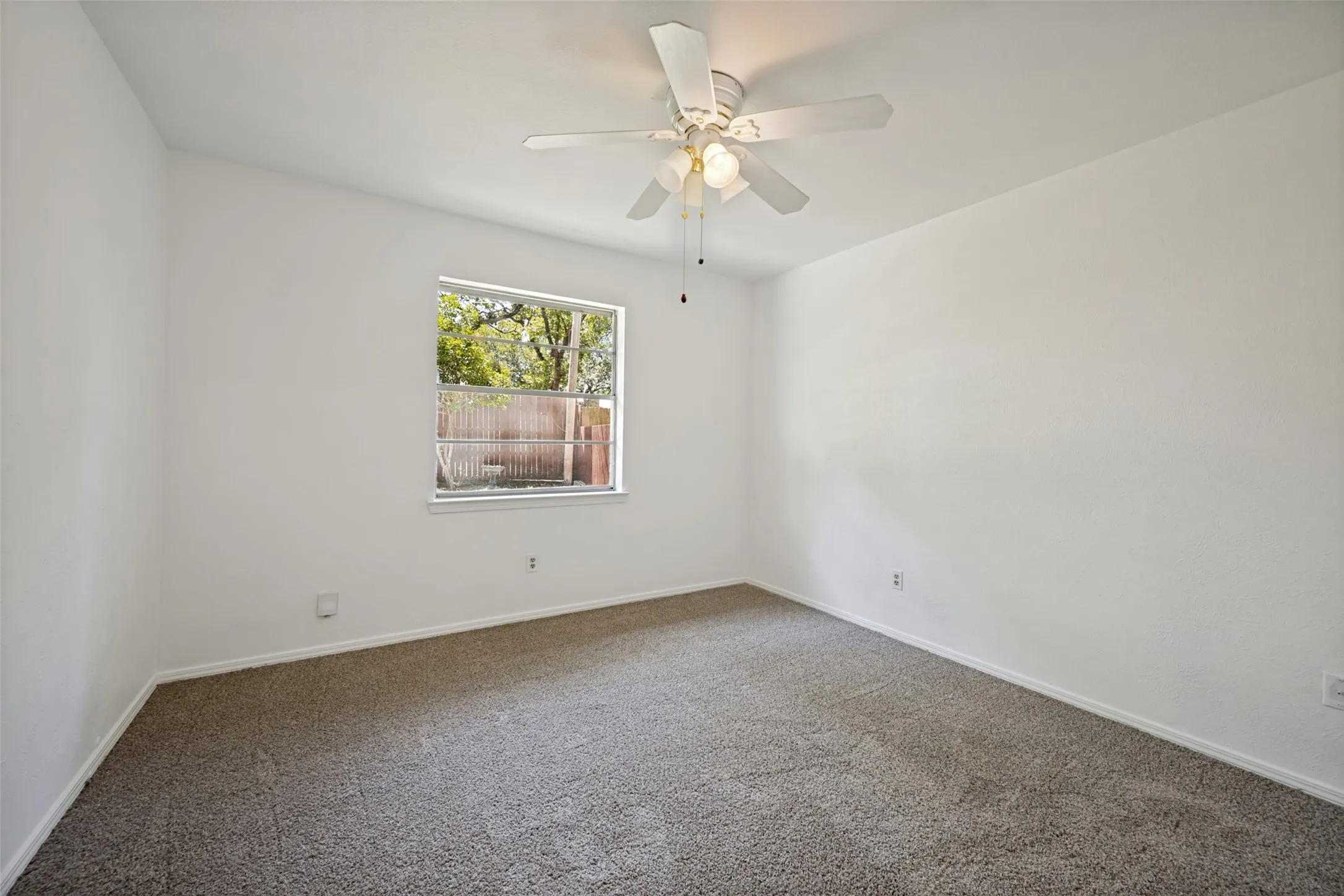 Neutral wall finishes with a window, ceiling fan, and carpeted flooring