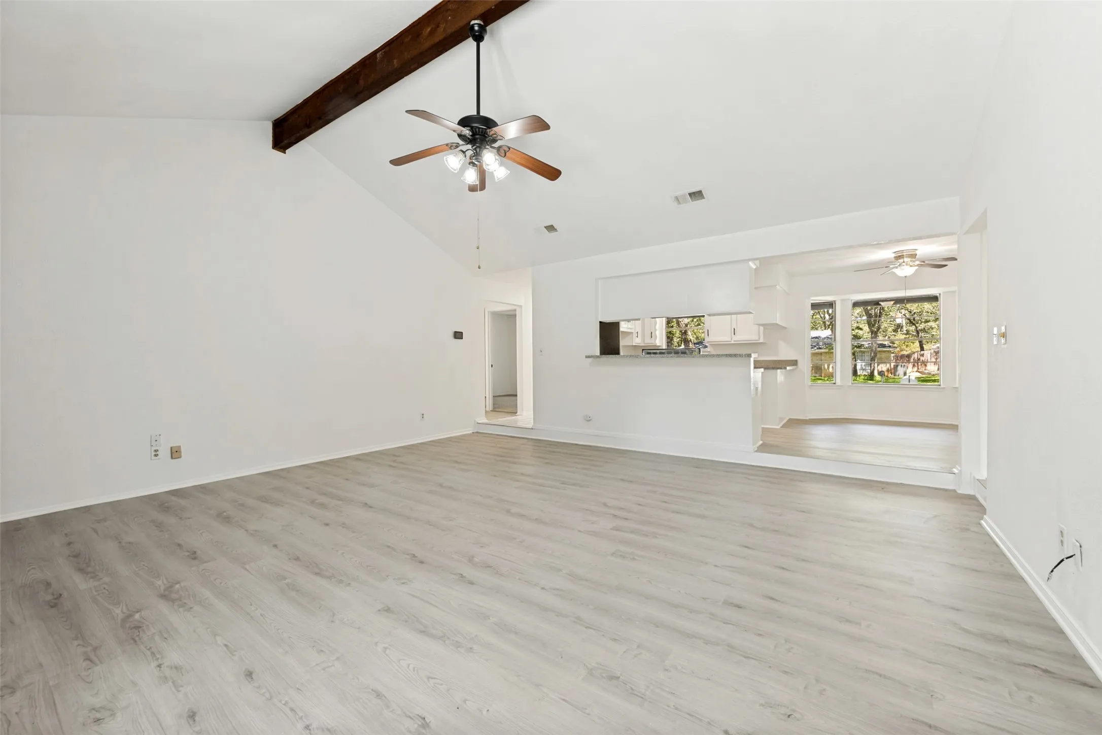 Vaulted ceiling with exposed wood beam, wood-finish flooring, recessed lighting, and a ceiling fan