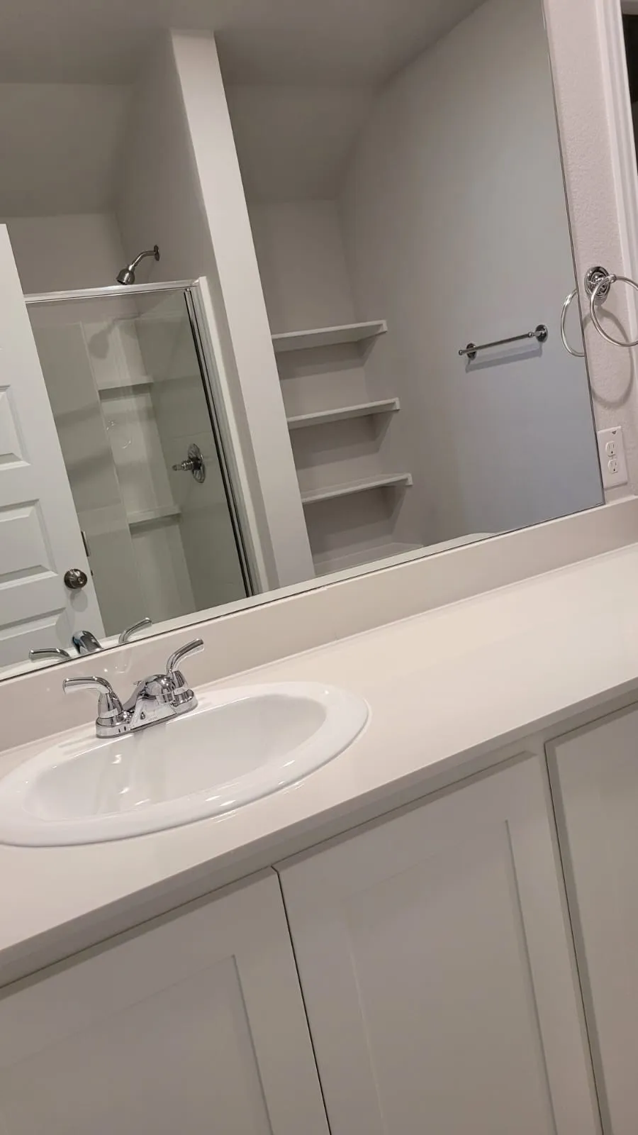 Vanity with integrated sink, polished chrome faucet, and white shaker-style cabinetry