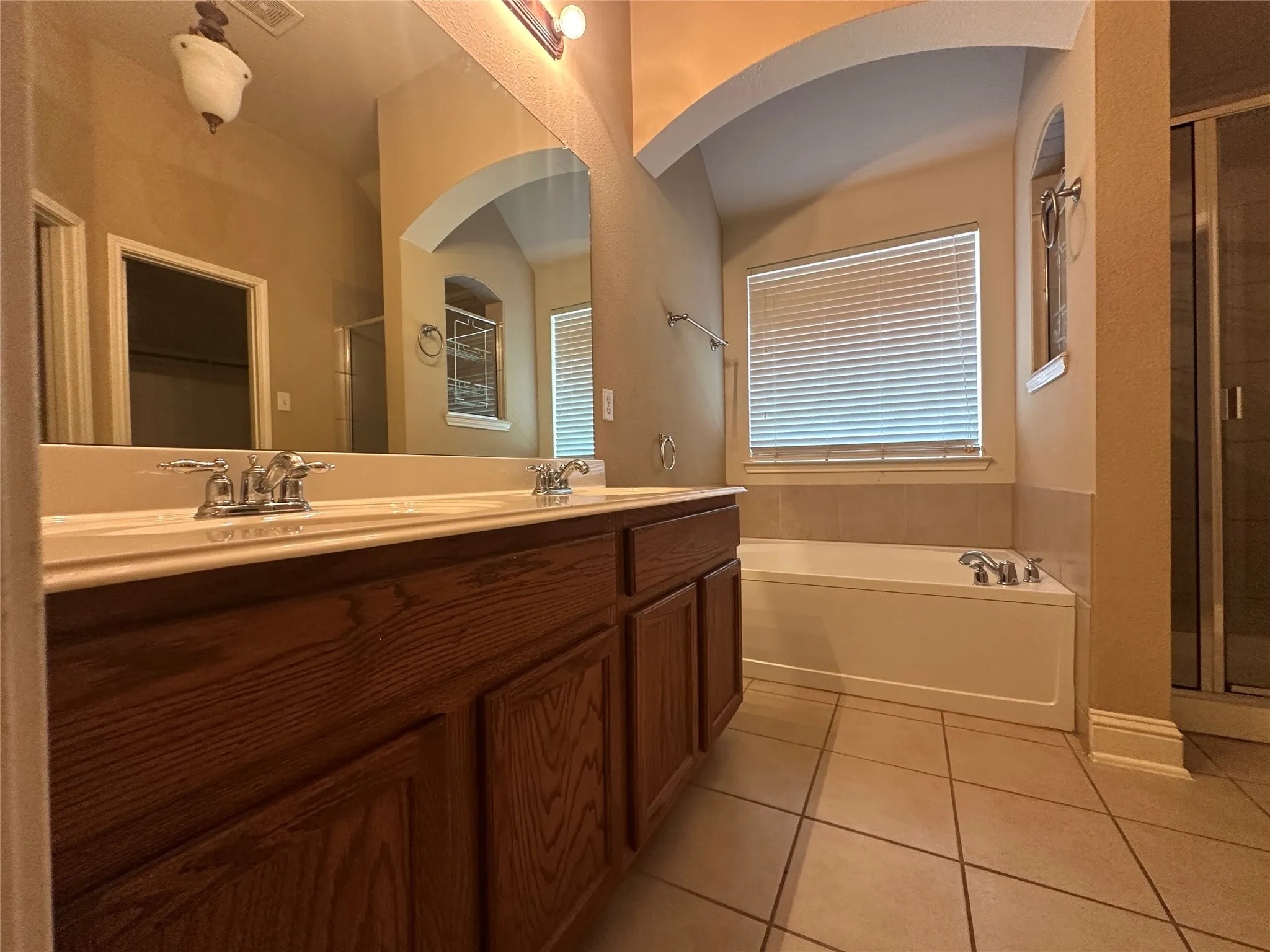 Double vanity with wood-finish cabinetry, drop-in sinks, and chrome-finish faucets