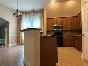 Kitchen featuring wood-finish cabinetry, built-in microwave, and tile flooring