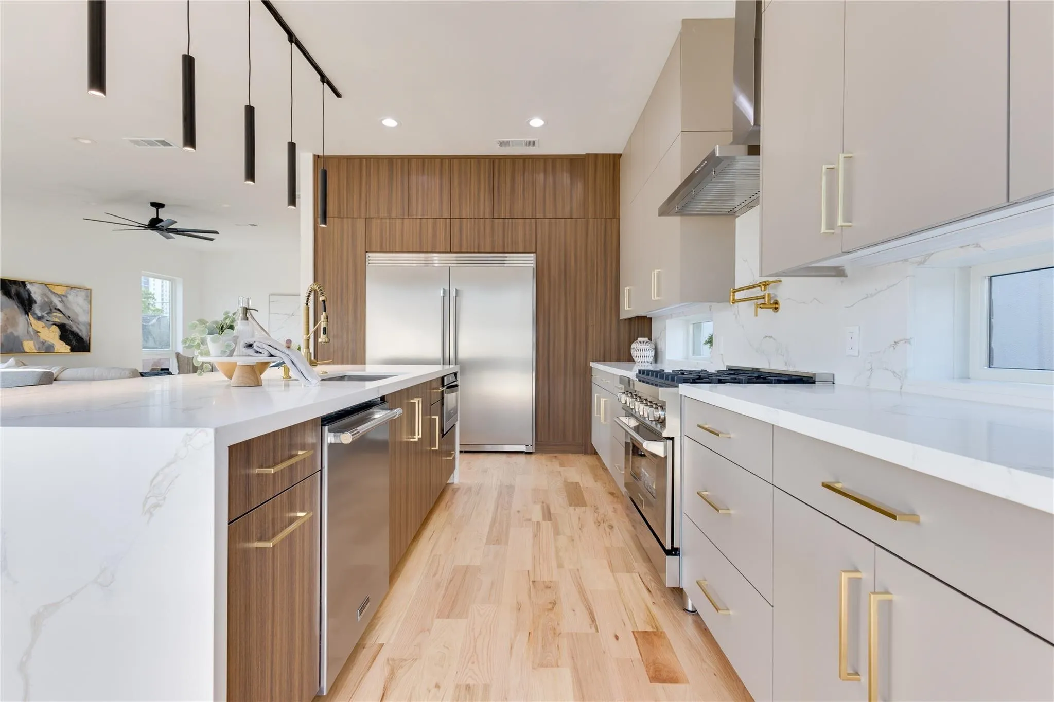 Kitchen featuring tasteful backsplash, premium appliances, light stone counters, wall chimney exhaust hood, and light wood-type flooring