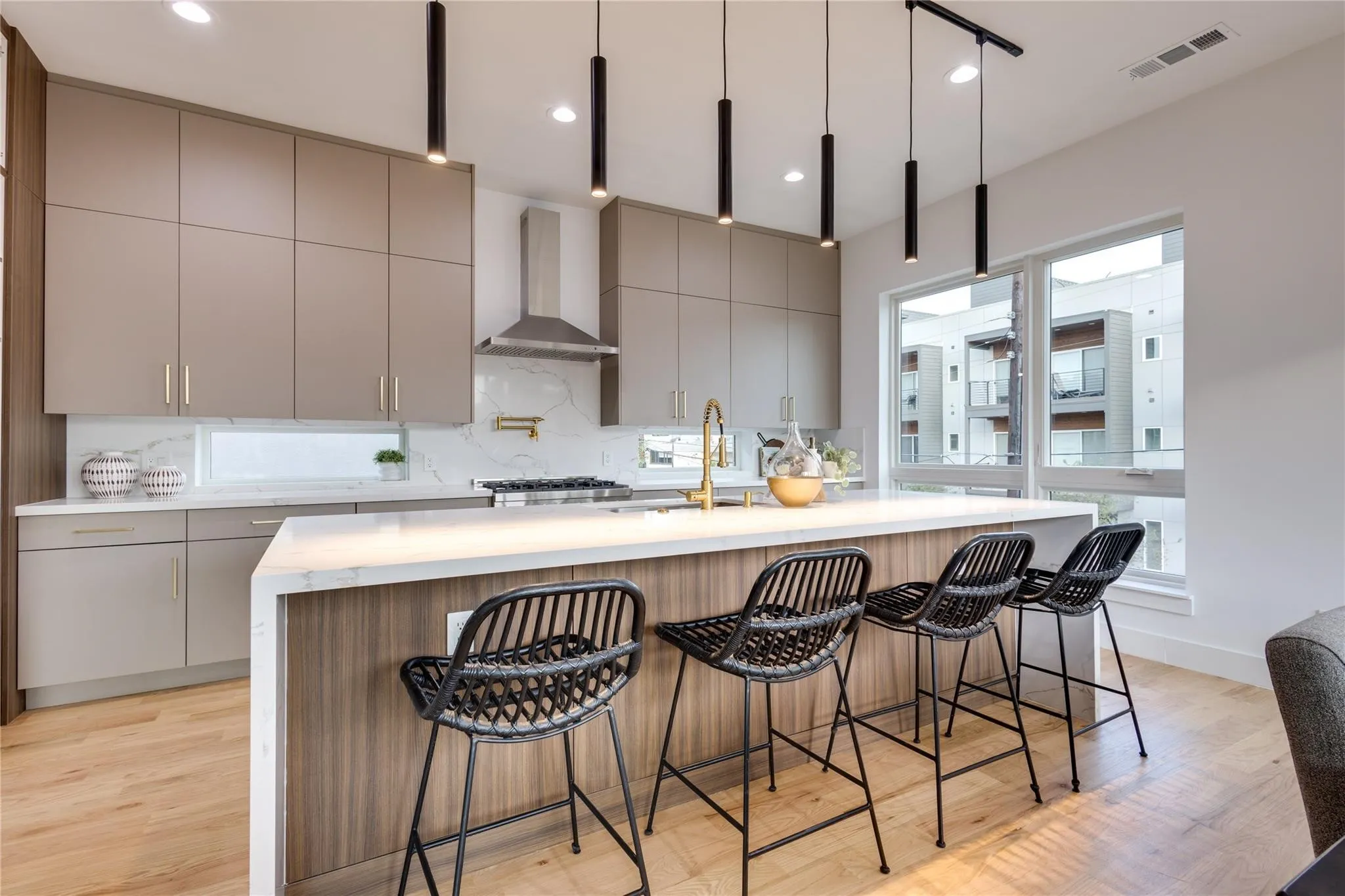 Kitchen with sink, gray cabinetry, wall chimney range hood, a kitchen island with sink, and backsplash