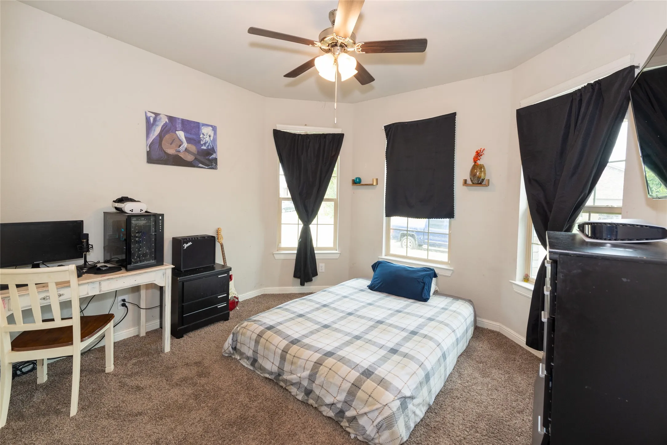 Bay window with multiple windows, ceiling fan with light fixture, and plush carpet flooring