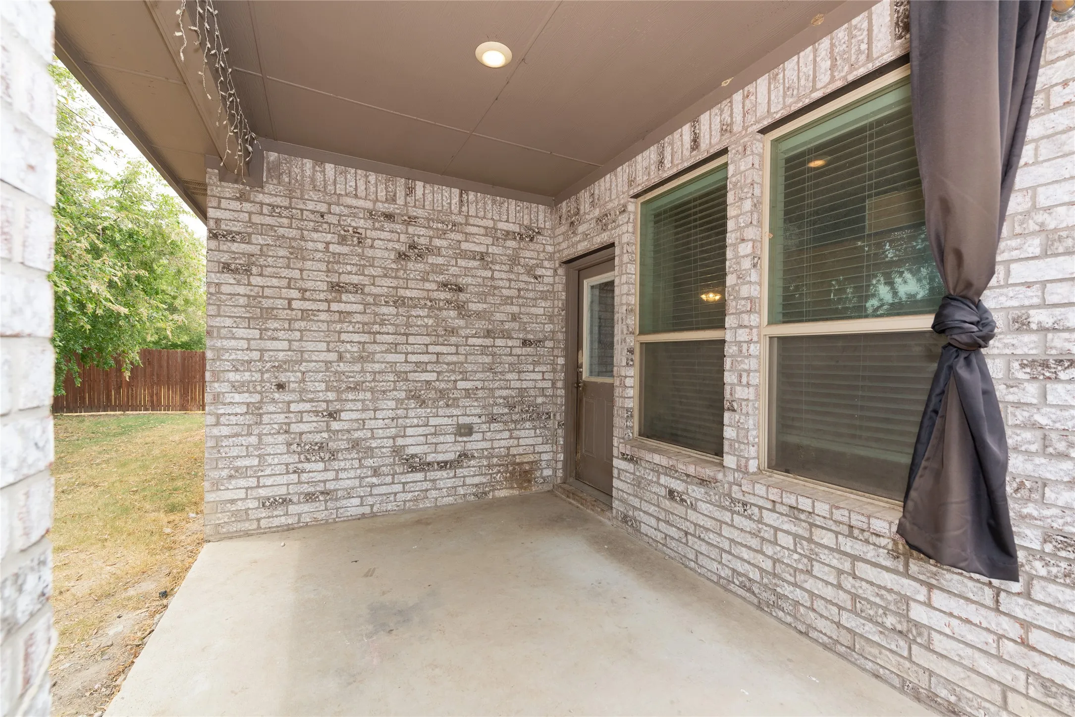 Covered patio with brick exterior, concrete flooring, and recessed lighting