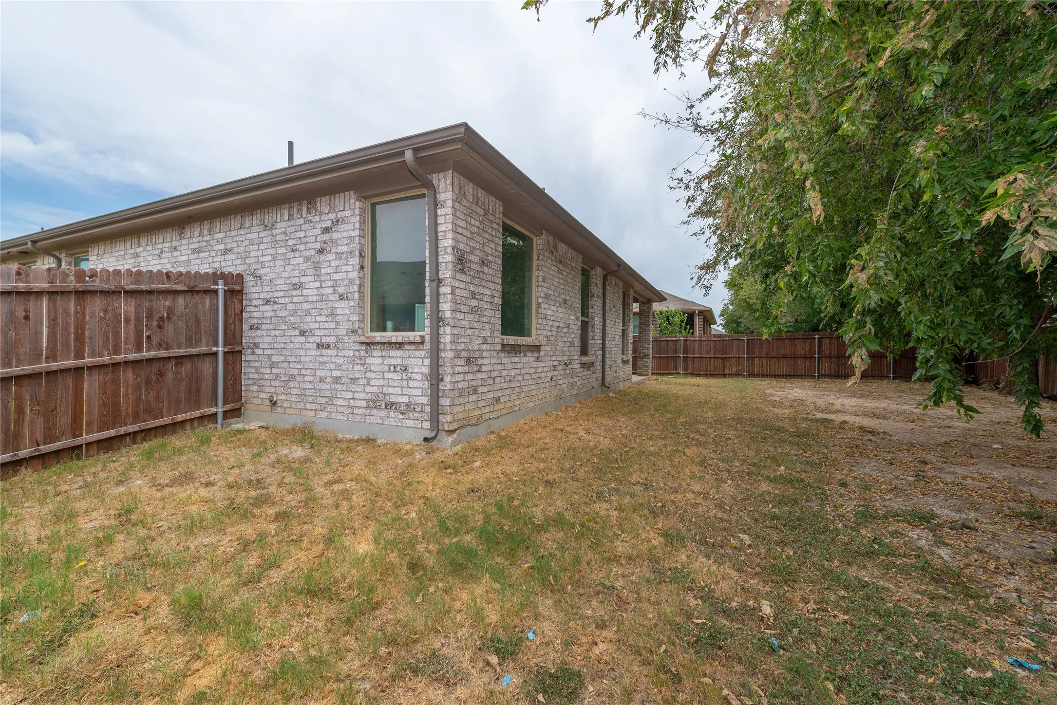 Brick exterior construction, multiple windows, and a complete wood fence