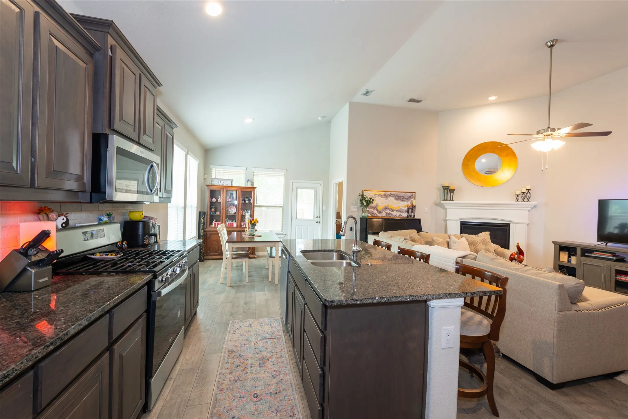 Kitchen island with an undermount sink, granite countertops, and dark wood-finish cabinetry