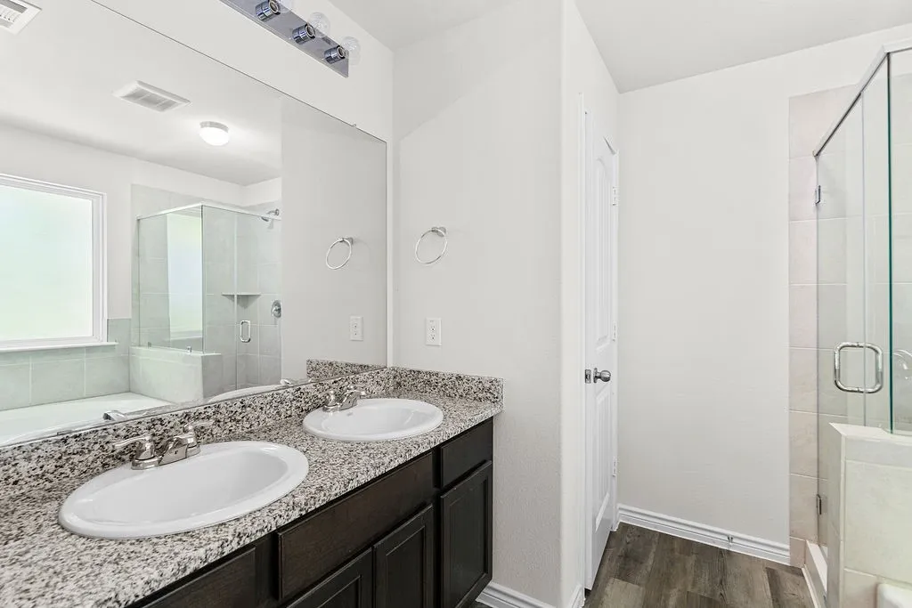Dual vanity with integrated sinks, granite-style countertop, and dark wood-finish cabinetry