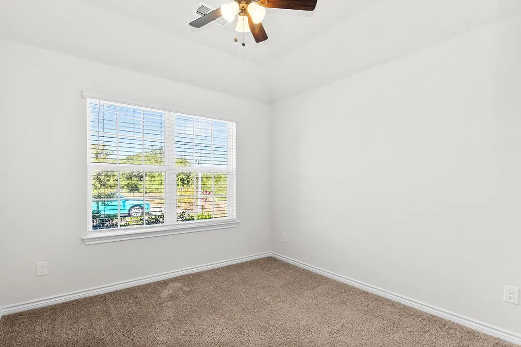 Vaulted ceiling with a ceiling fan, window with blinds, and neutral carpeting