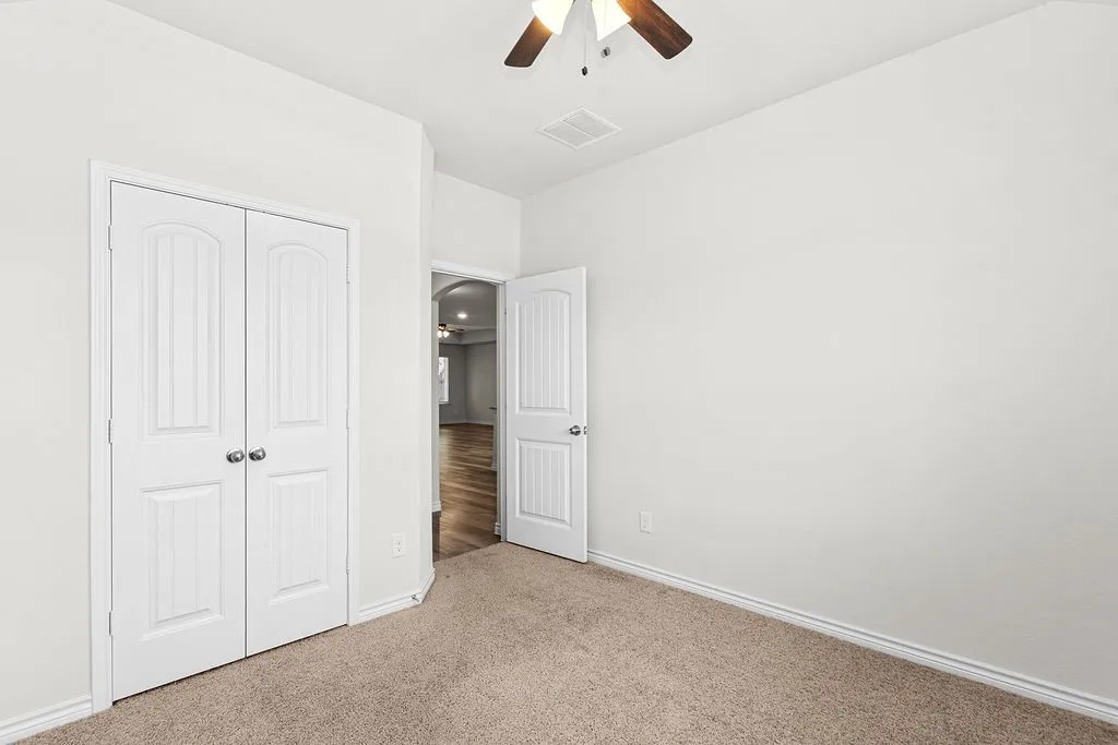 Carpeted flooring, white walls, white paneled doors, ceiling fan with light fixture, white trim