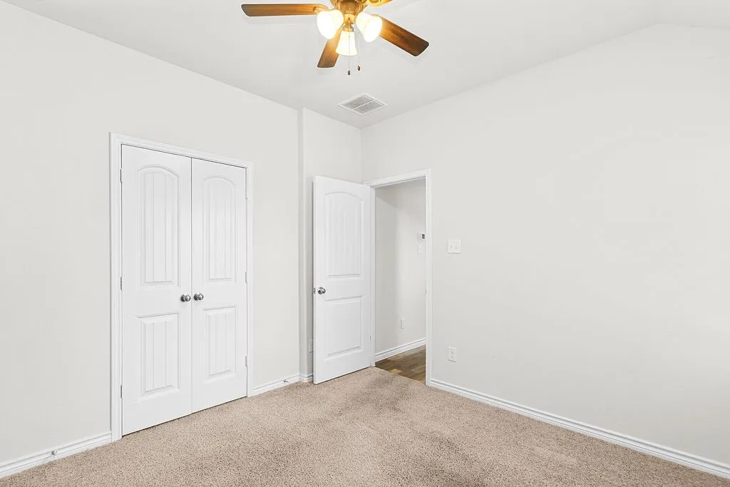 Ceiling fan with integrated lighting, carpeted flooring, and white paneled doors