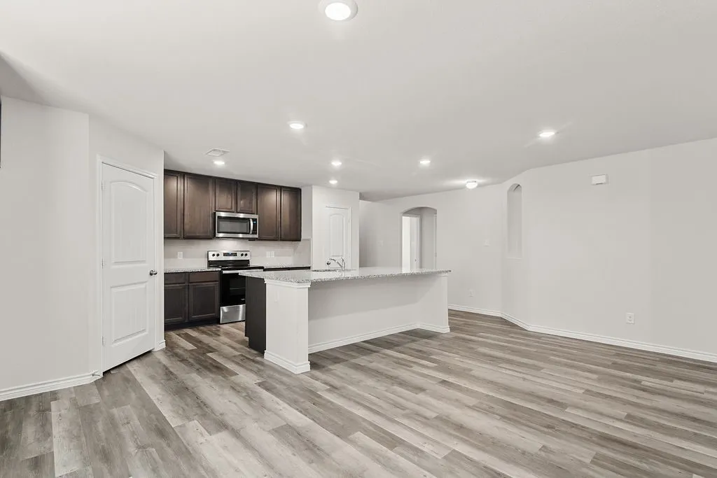 Recessed lighting illuminates wood-finish flooring