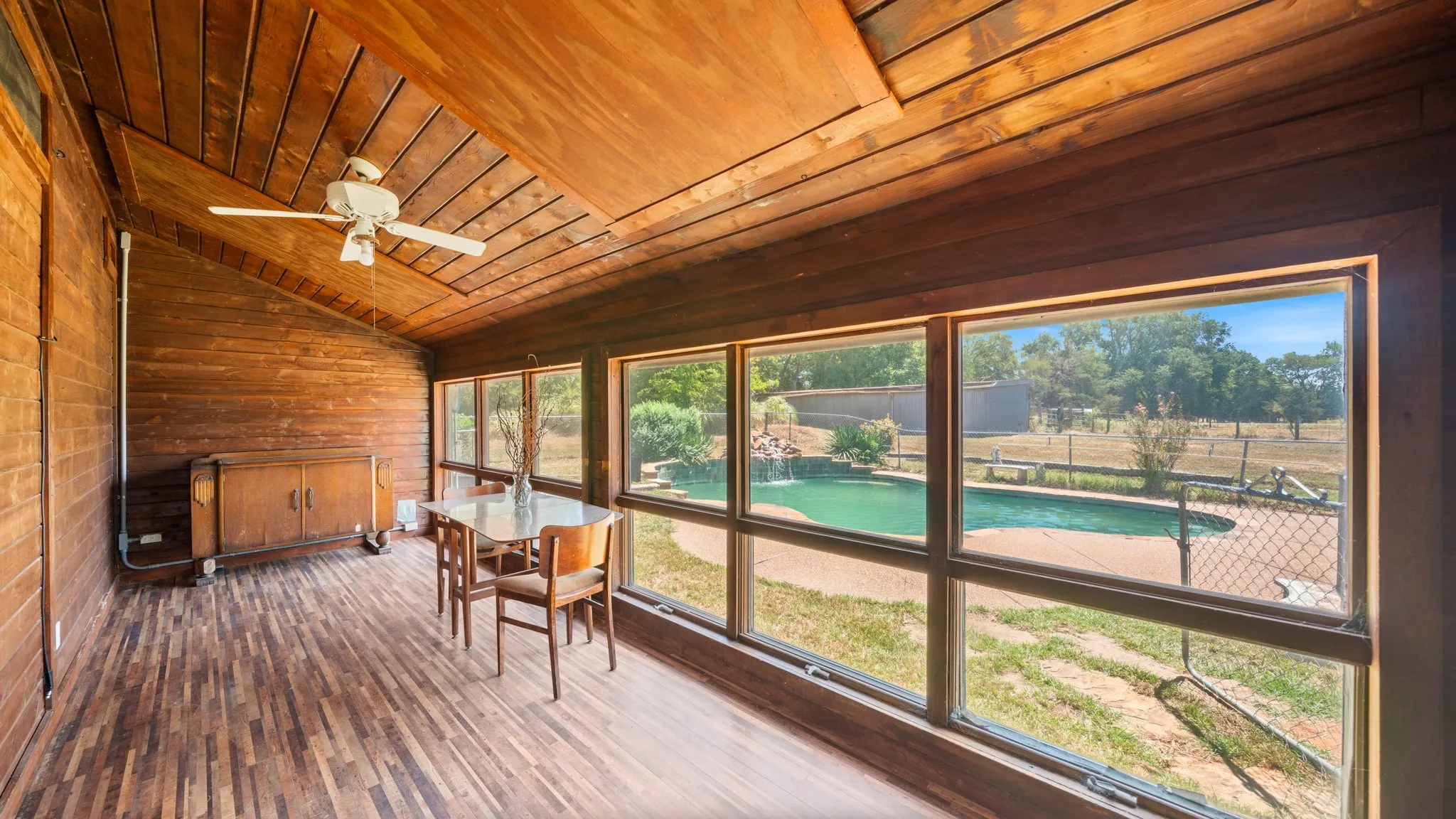 Wood-paneled room with an angled wood ceiling, featuring a ceiling fan and a built-in wood cabinet