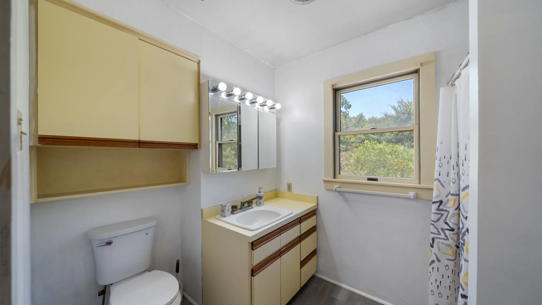 White vanity with integrated sink, overhead lighting, and built-in medicine cabinet