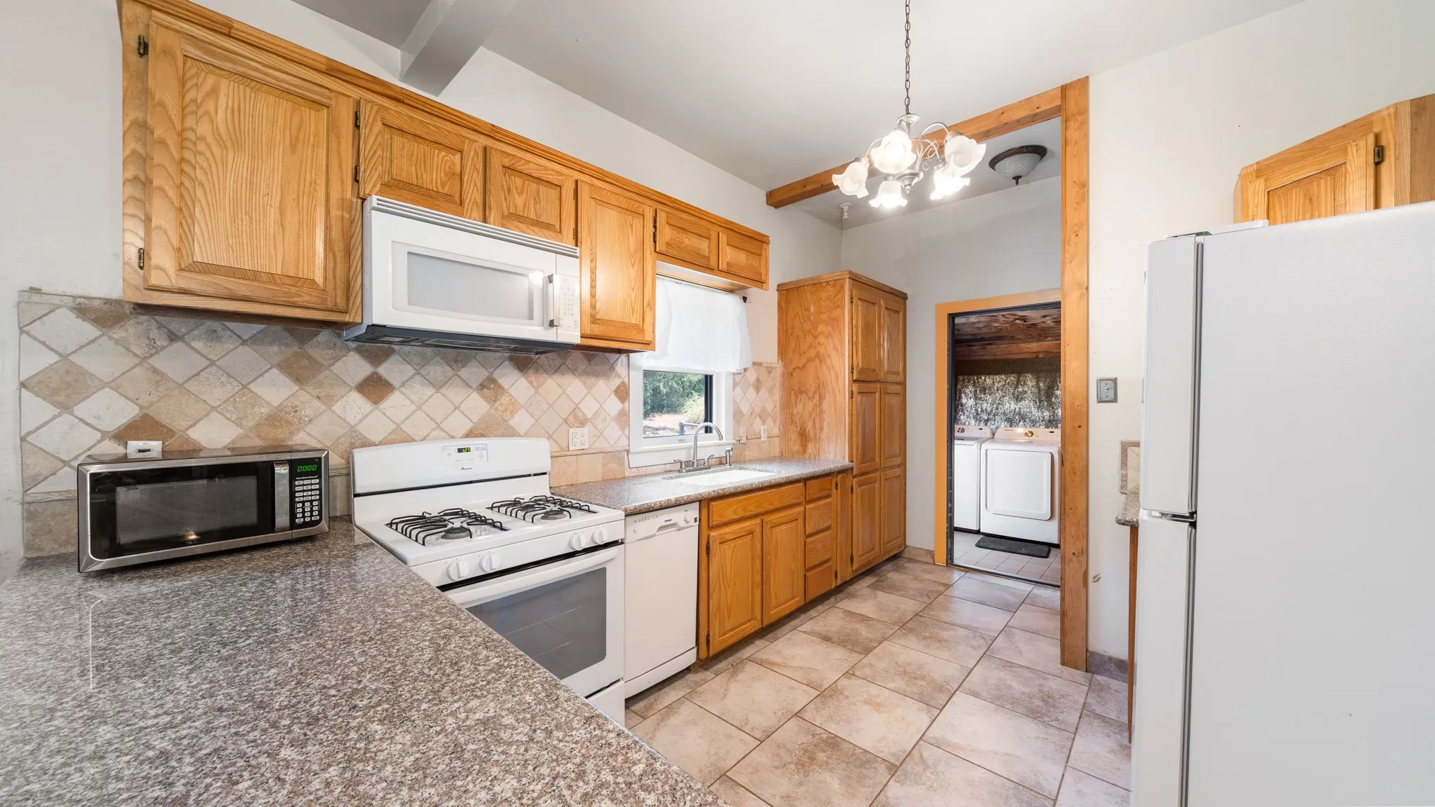 Kitchen featuring wood cabinetry, solid surface countertops, tile flooring, and a tile backsplash