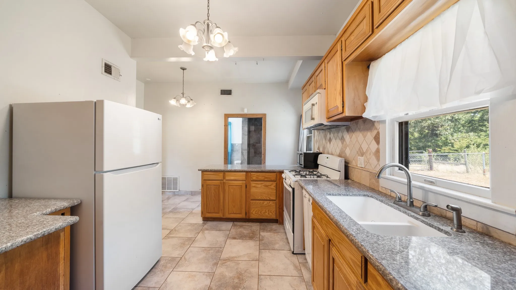 Kitchen featuring wood cabinetry, granite-style countertops, tile flooring, and a white sink with a gooseneck faucet