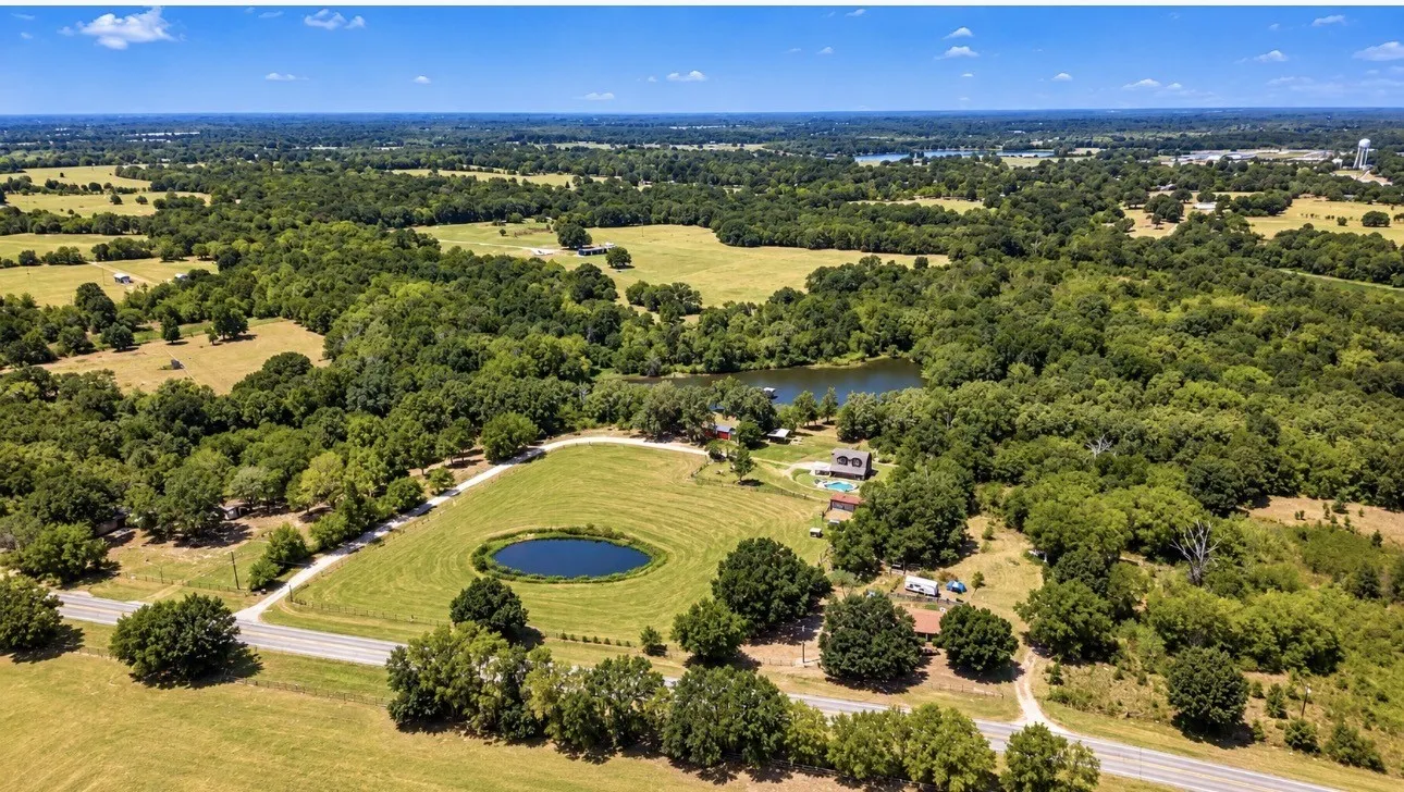Expansive land parcel featuring multiple ponds, mature trees, and a road frontage