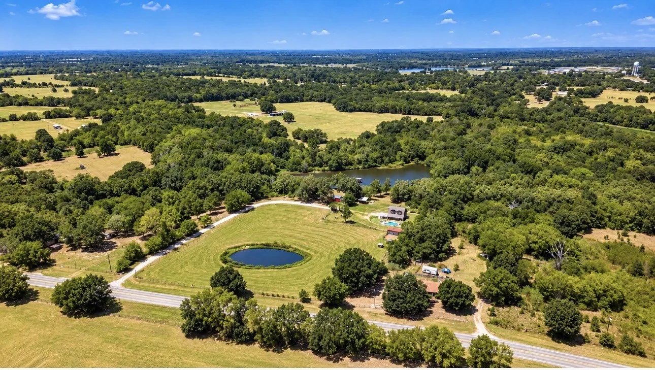 Expansive property featuring a private pond, mature trees, and a road