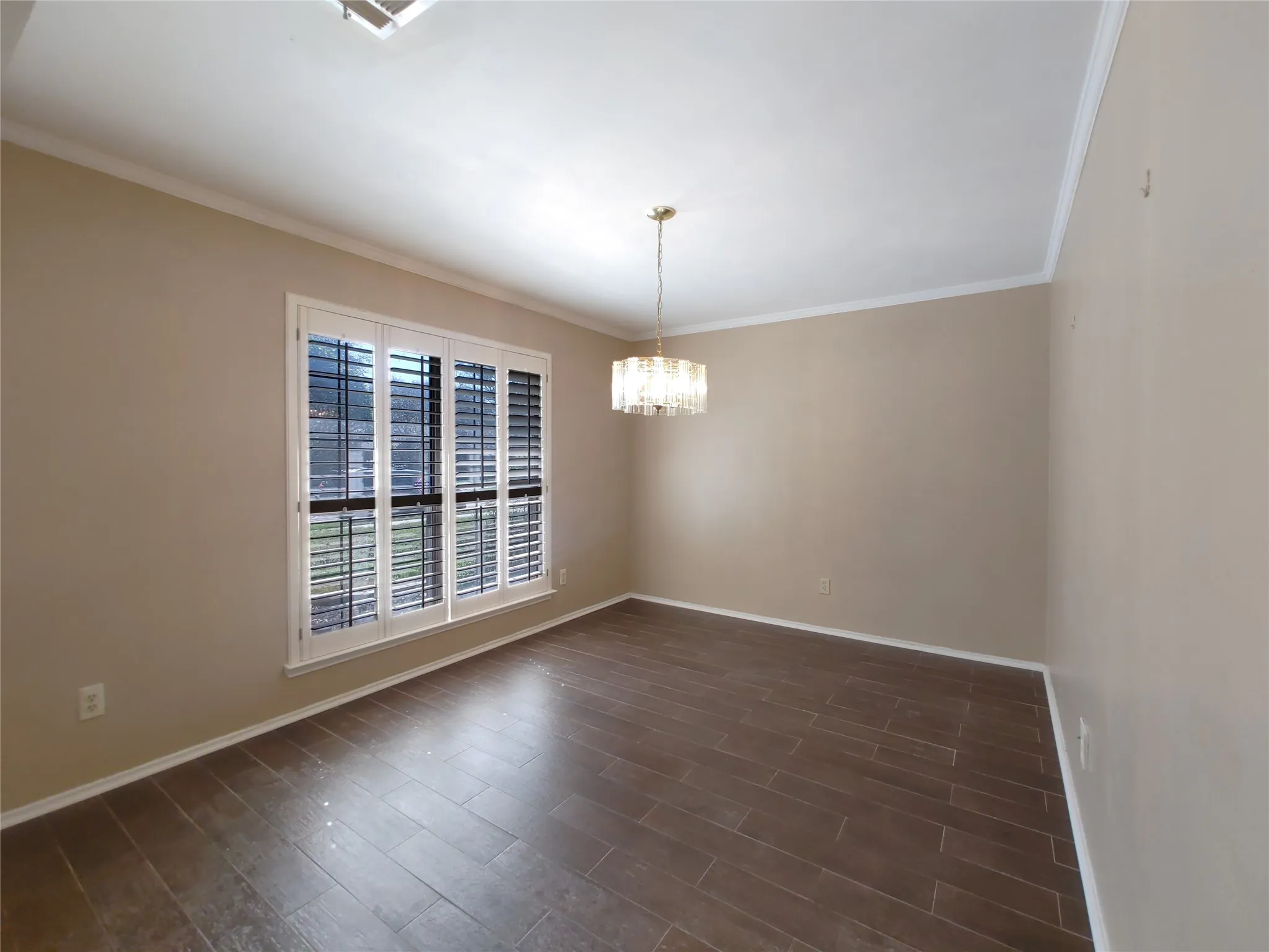 Wood-finish flooring, crown molding, a crystal chandelier, and window shutters
