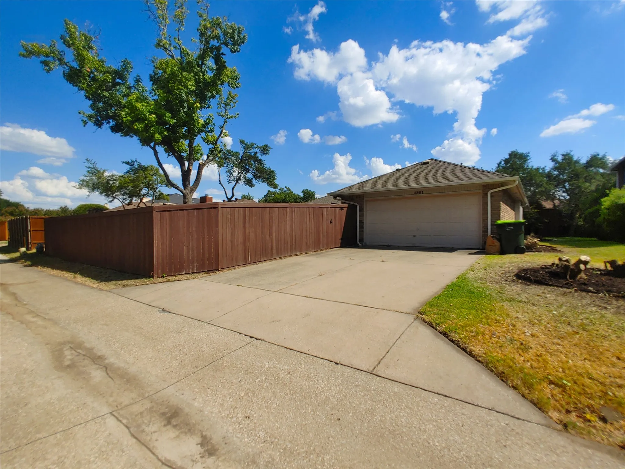 Attached two-car garage, concrete driveway, and brown privacy fencing
