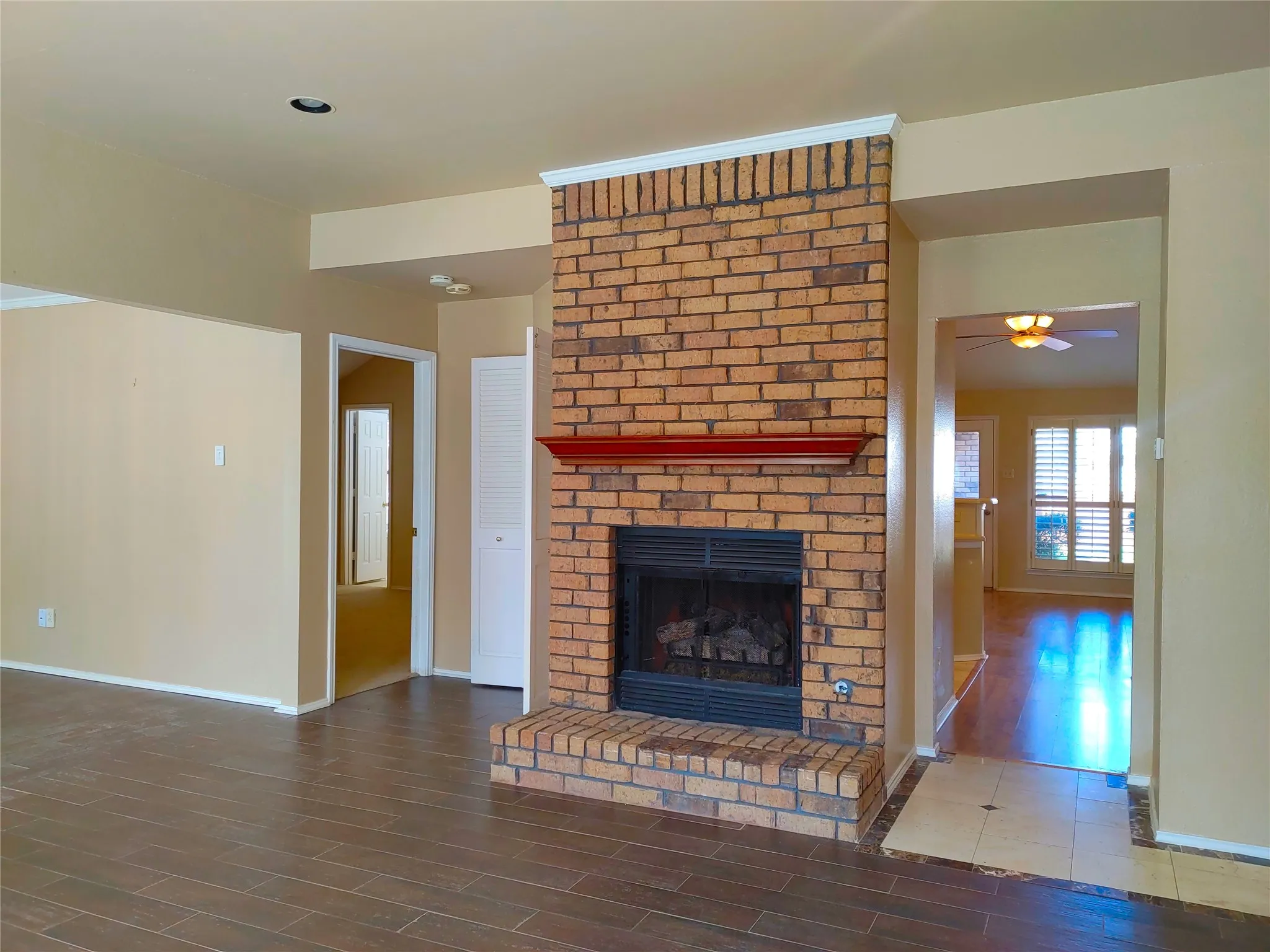 Brick fireplace with a red mantel and hearth, dark wood-finish flooring, recessed lighting, and white interior doors