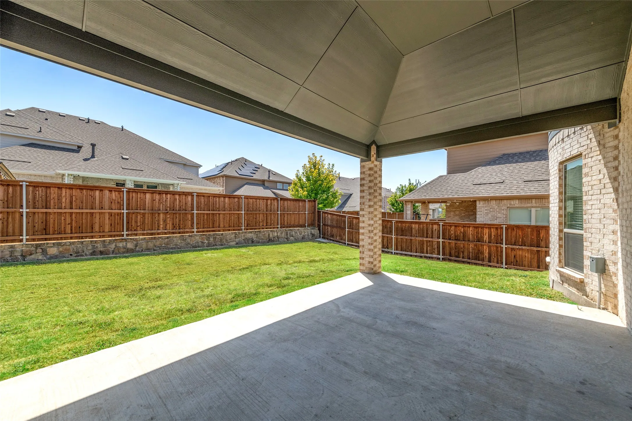 Covered outdoor patio with a concrete surface, supported by a brick column